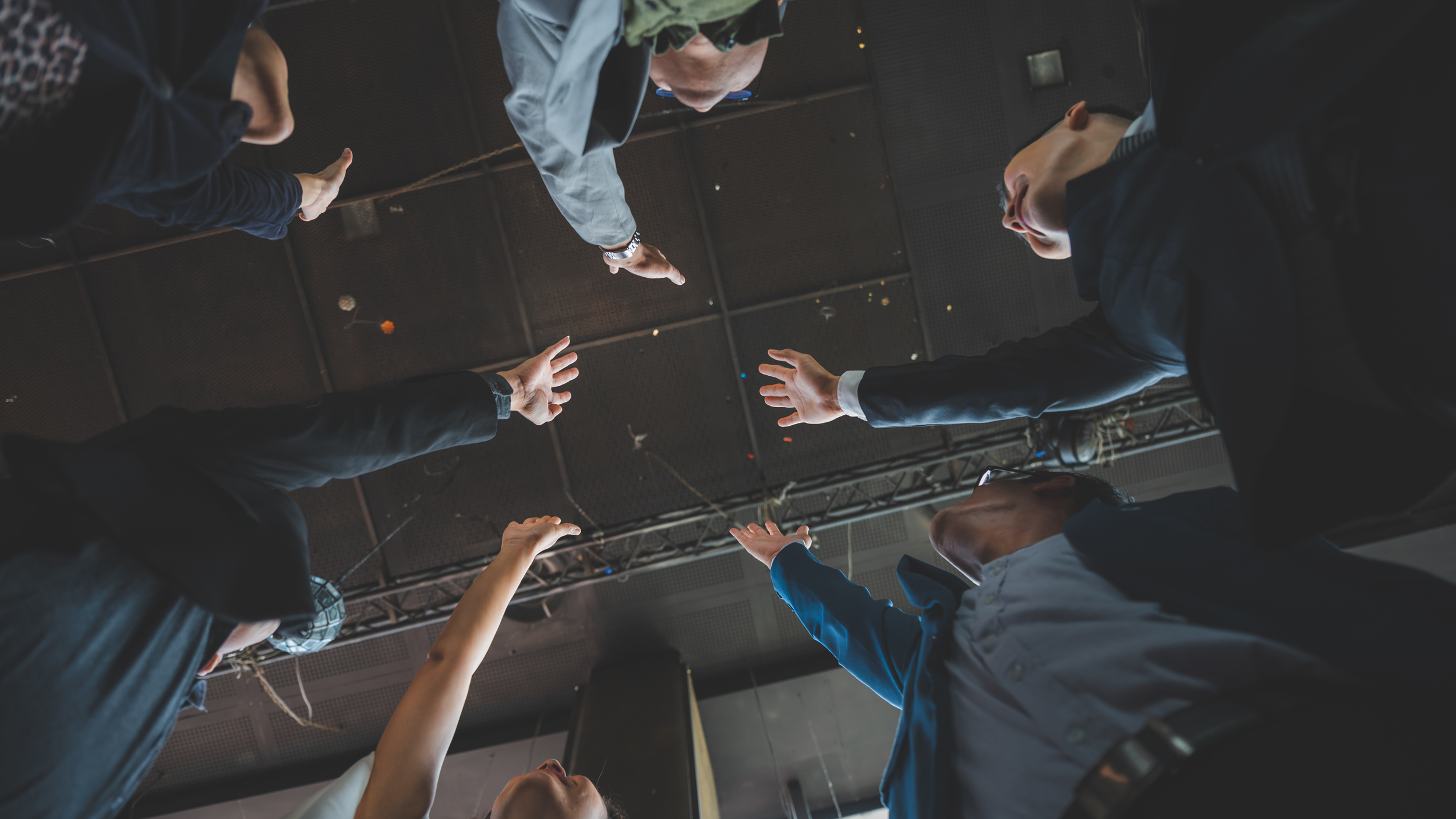 Groupe de personnes en costume se tenant par les mains en cercle, vu de dessous