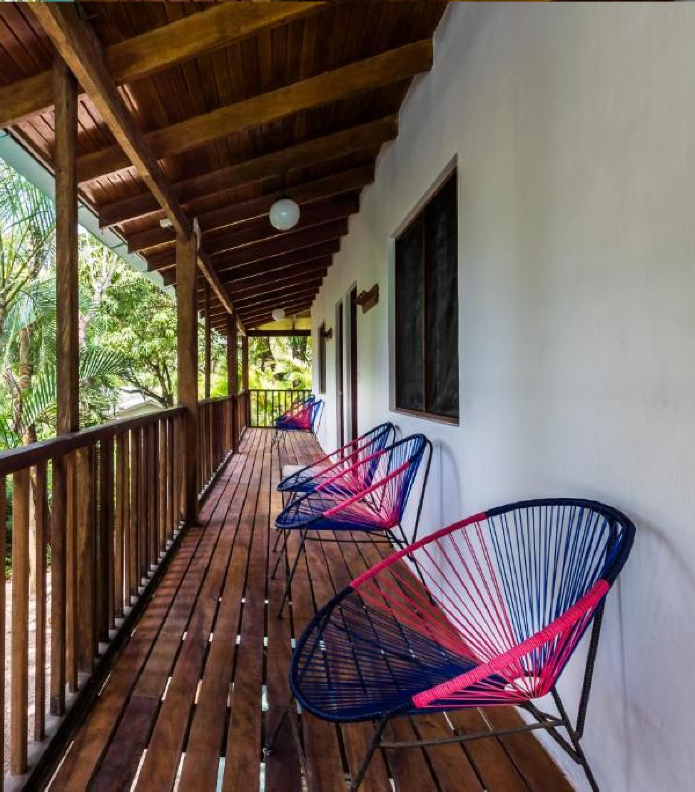 Wooden balcony railing and ceiling with chairs along the wall.