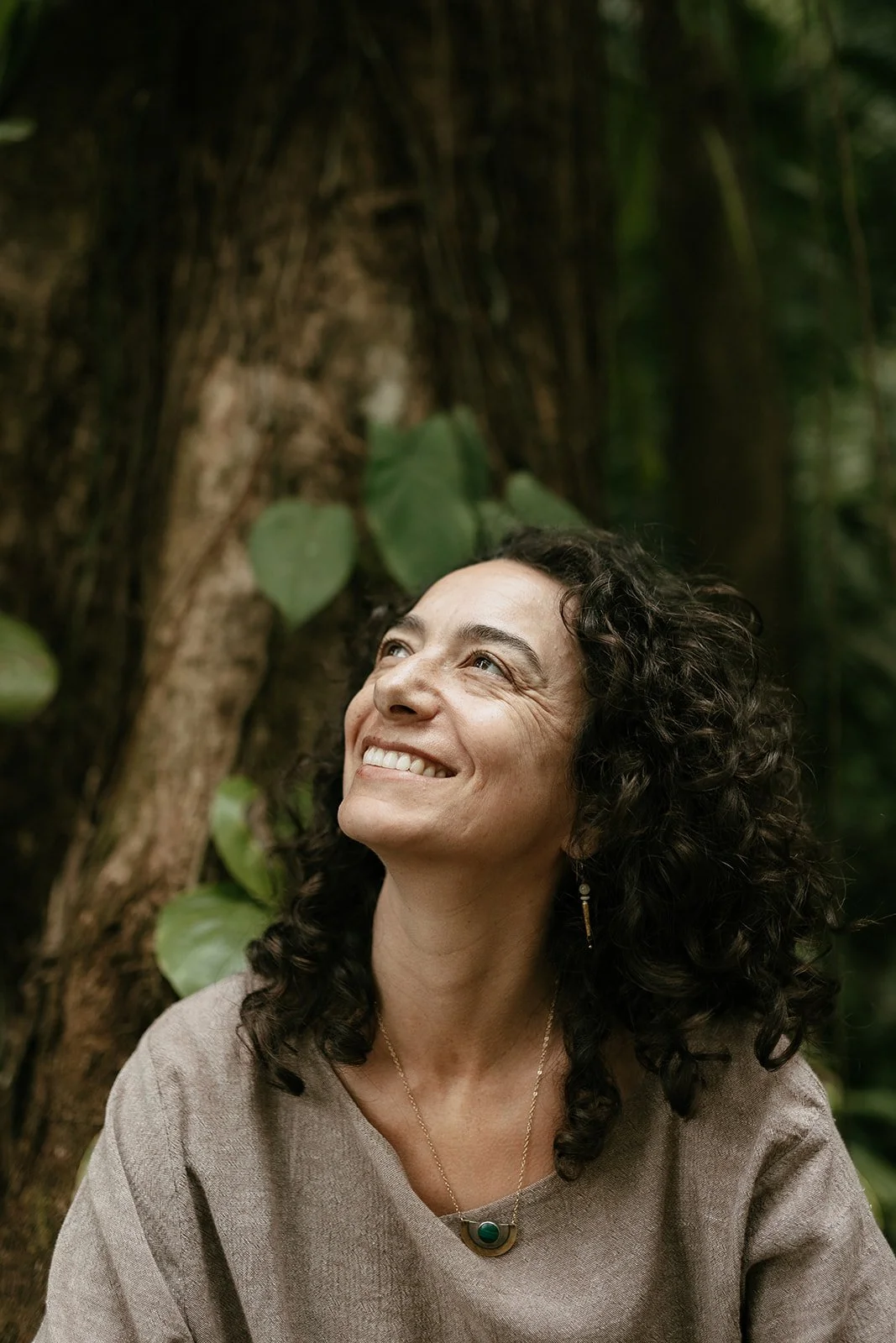 Alexis Lowenstein smiling and looking upward, outdoors in a forested area.