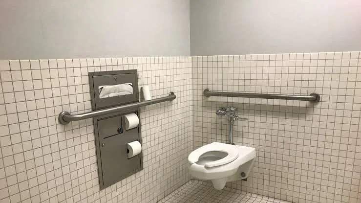 Accessible bathroom stall with a toilet, two grab bars, and a toilet paper holder.
