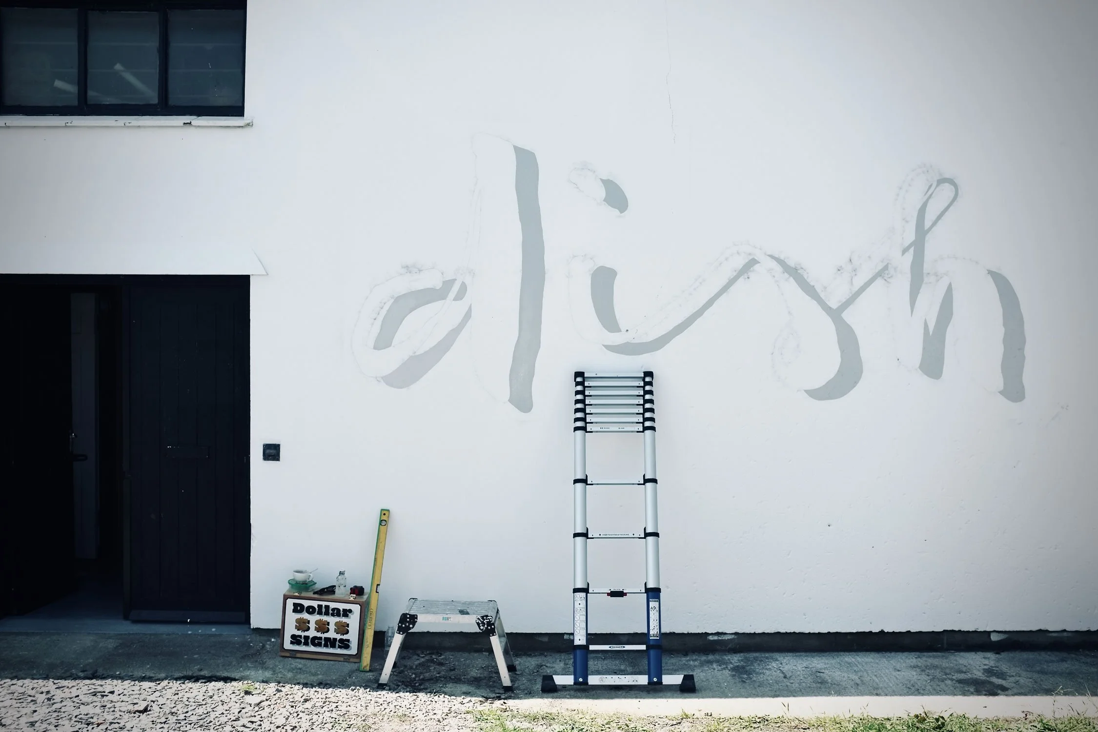 Traditional hand-painted script lettering on Dish Cornwall's prep kitchen exterior wall with traditional signwriting tools in Newquay.