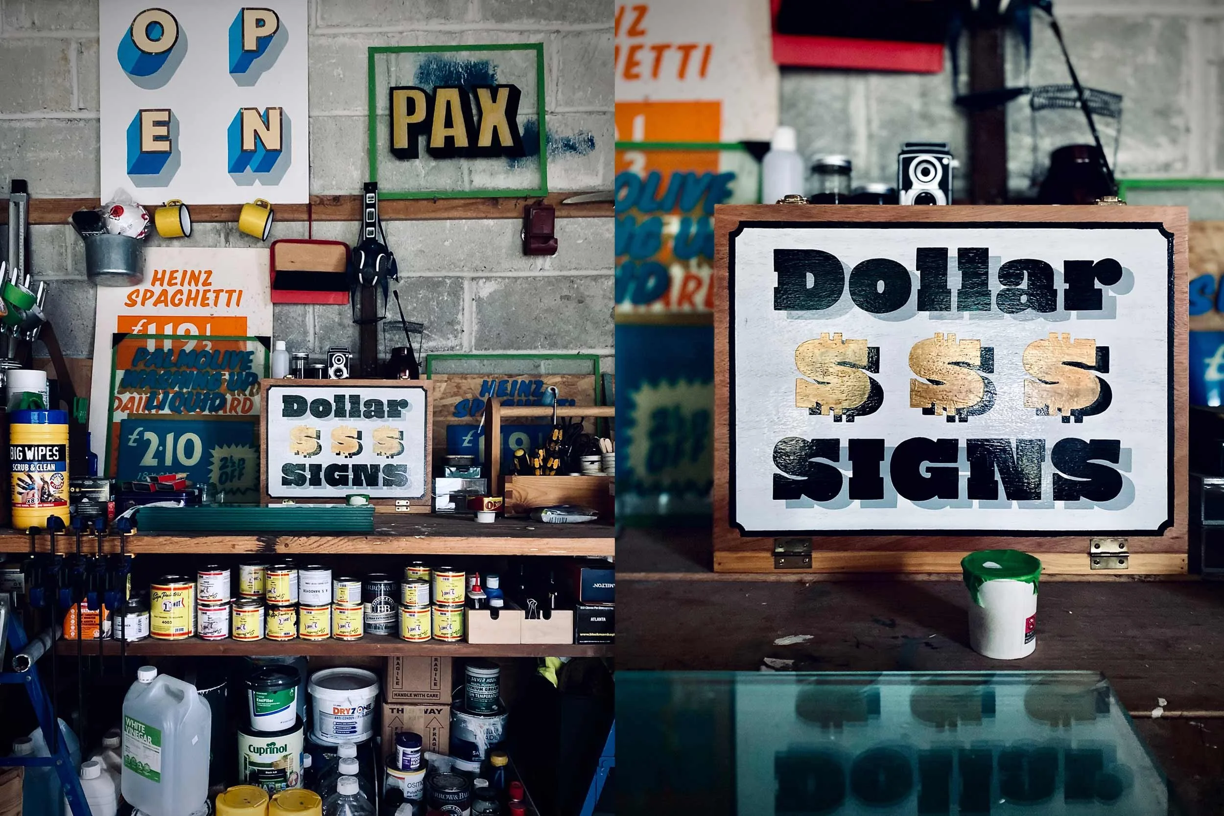 Hand-painted workshop signs, including Heinz Spaghetti and Dollar Signs branding, on a traditional signwriter workbench in St Agnes, Cornwall.