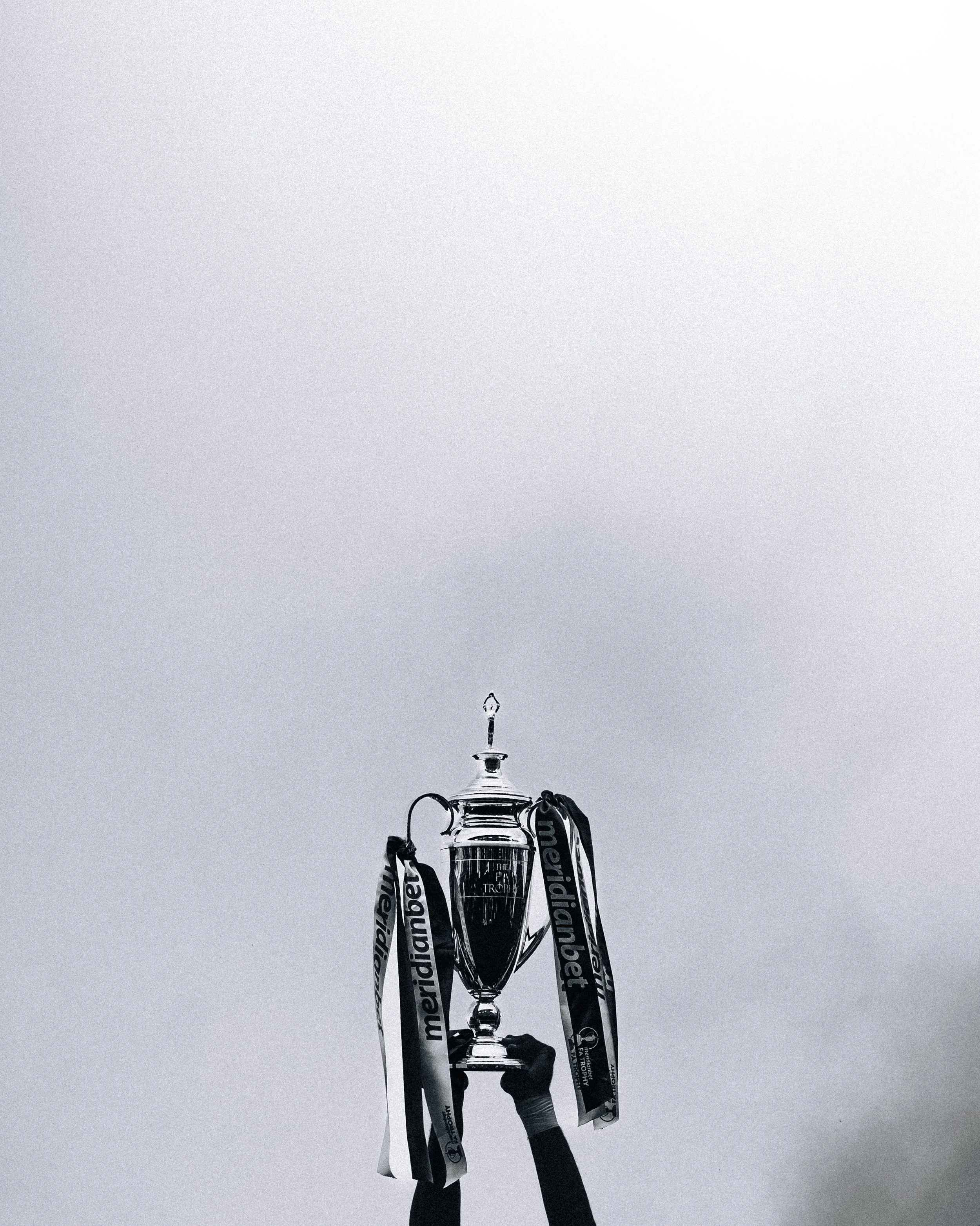 The FA trophy being used in celebrating a victory with a person's hand holding it.