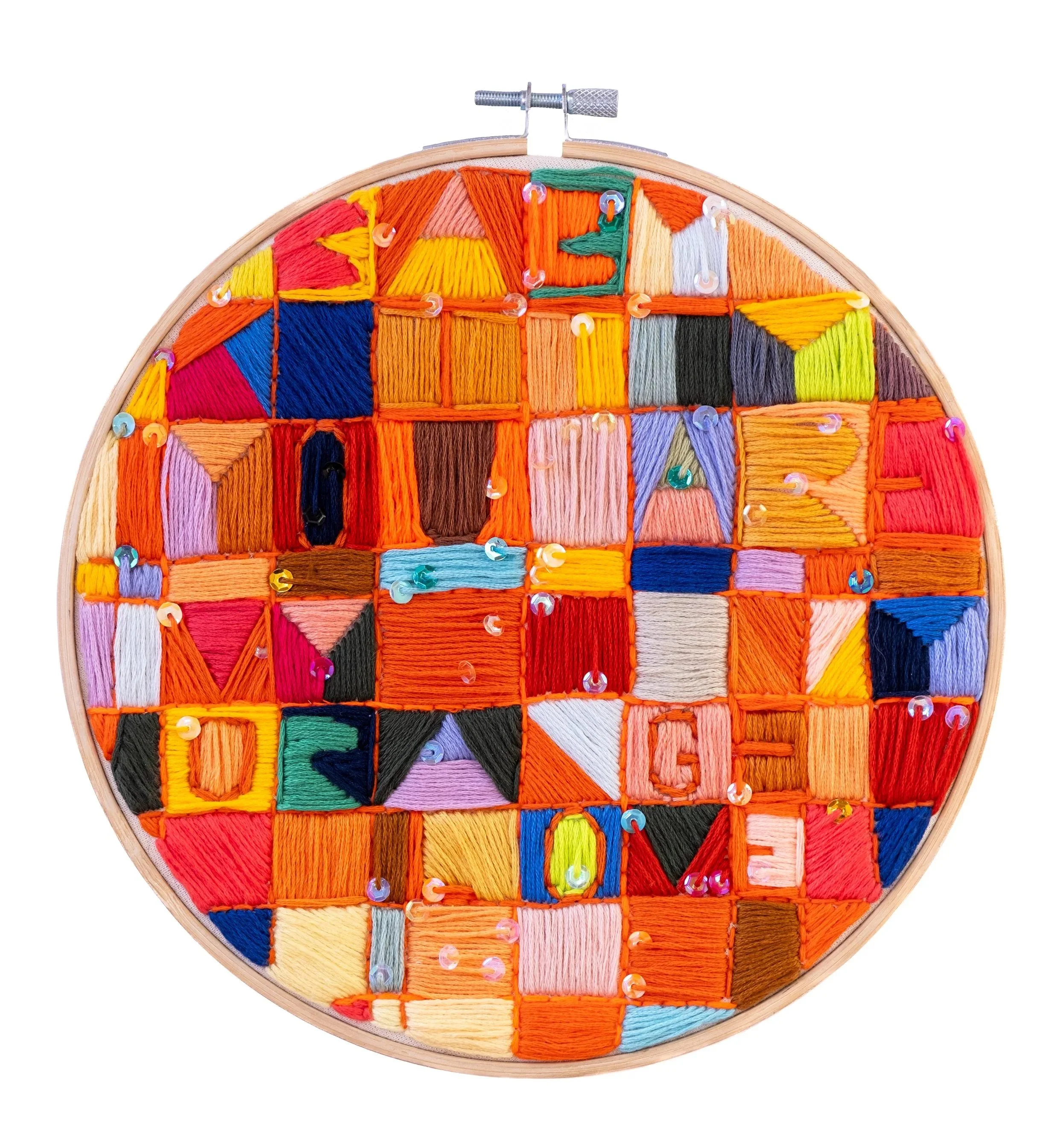Contemporary textile artwork. A wooden embroidery hoop filled with colorful embroidered squares and triangles, decorated with small sequins.