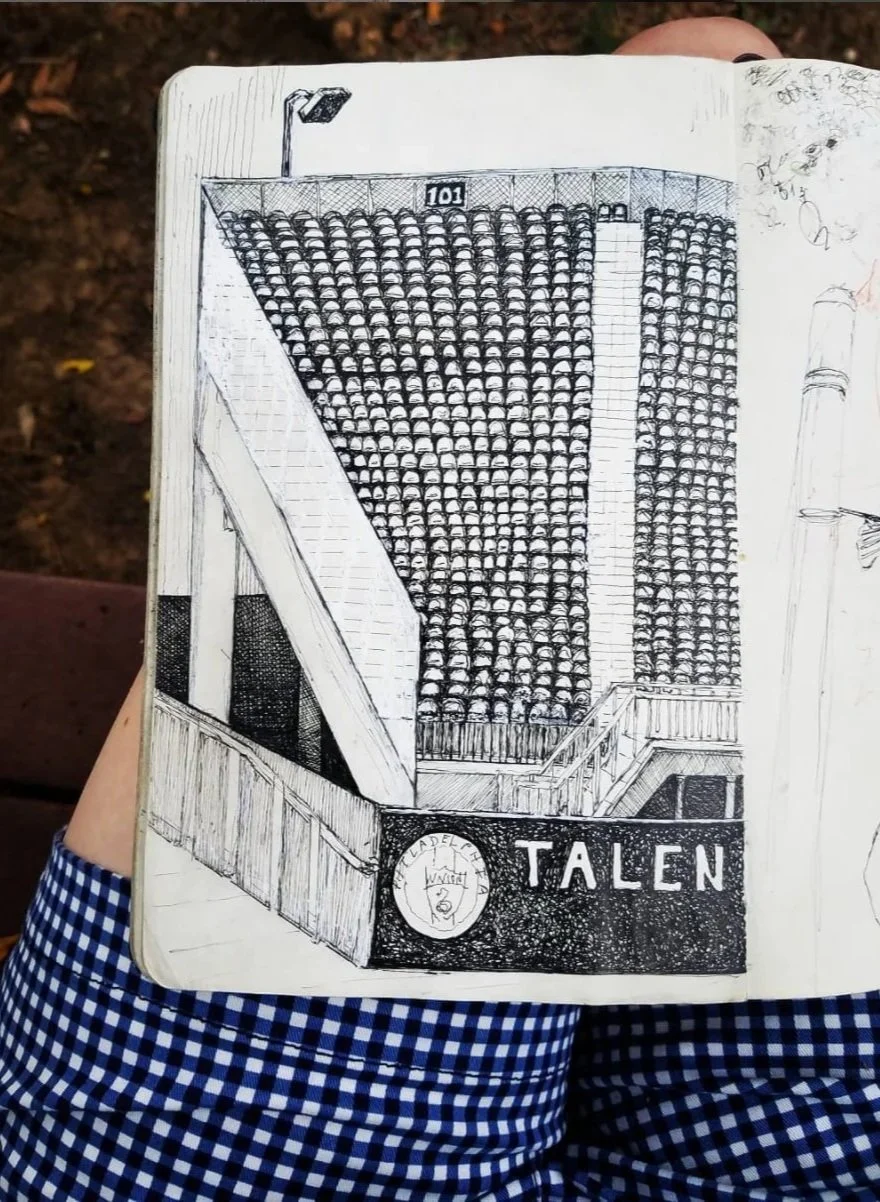 Hand-drawn sketch of a tall building with many windows, a streetlamp at the top, a sign with the number 101, and a banner reading 'TALEN' with a circular emblem below.