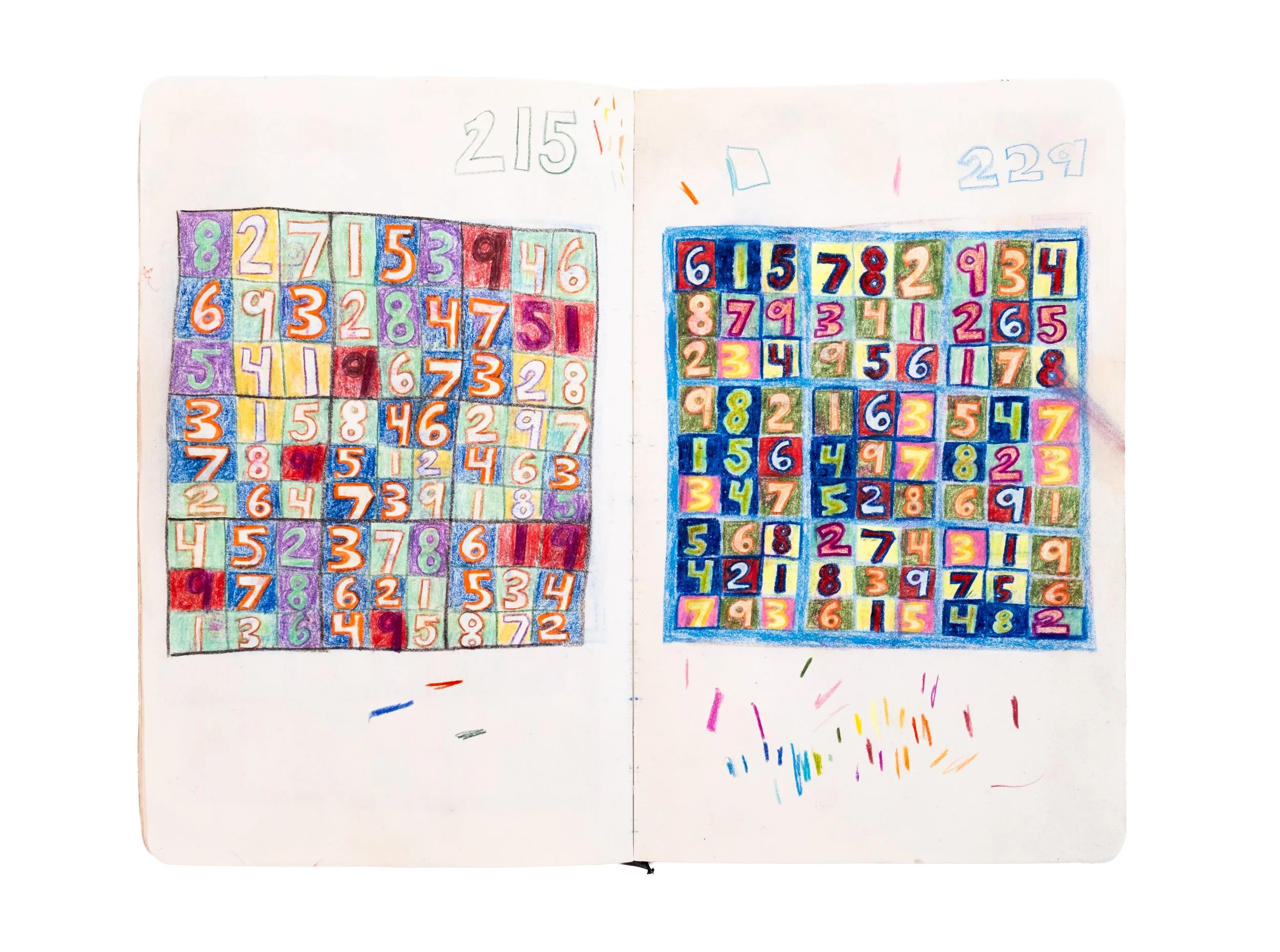 Open sketchbook with colorful calendar or puzzle of numbers 1 to 9, with some numbers repeated, in a grid pattern on both pages, with the left page showing numbered squares from 1 to 9 and the right page displaying similar squares filled with numbers