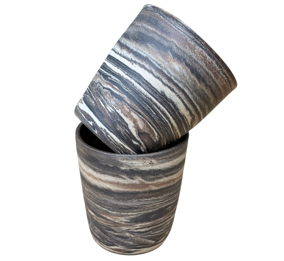 A two-piece set of cylindrical stone containers with a marbled pattern; one container is upright and the other is tilted inside.