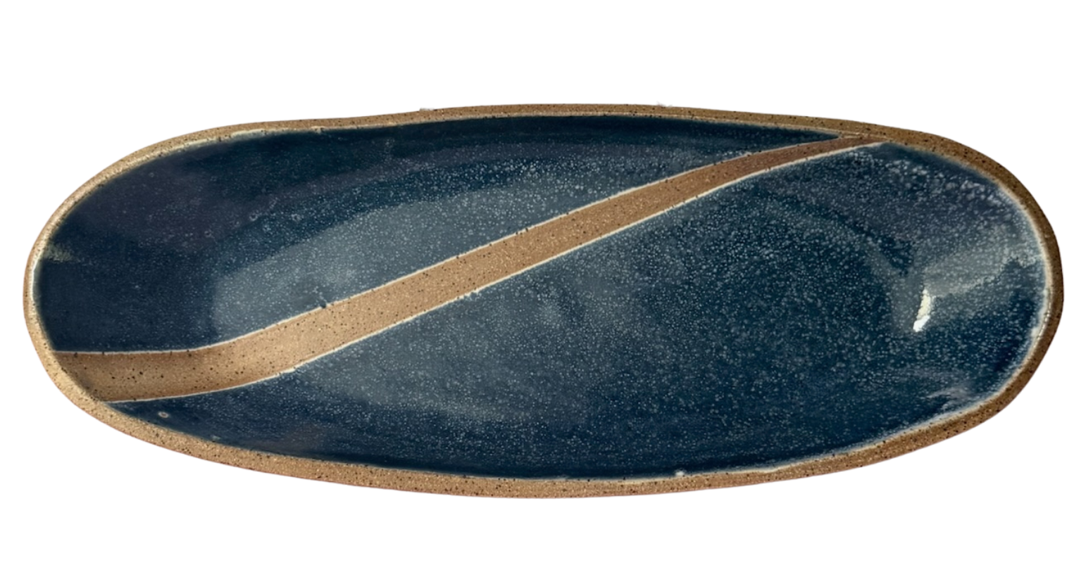 Oval ceramic plate with dark blue glaze, brown speckled rim, and a beige stripe running diagonally across the center.