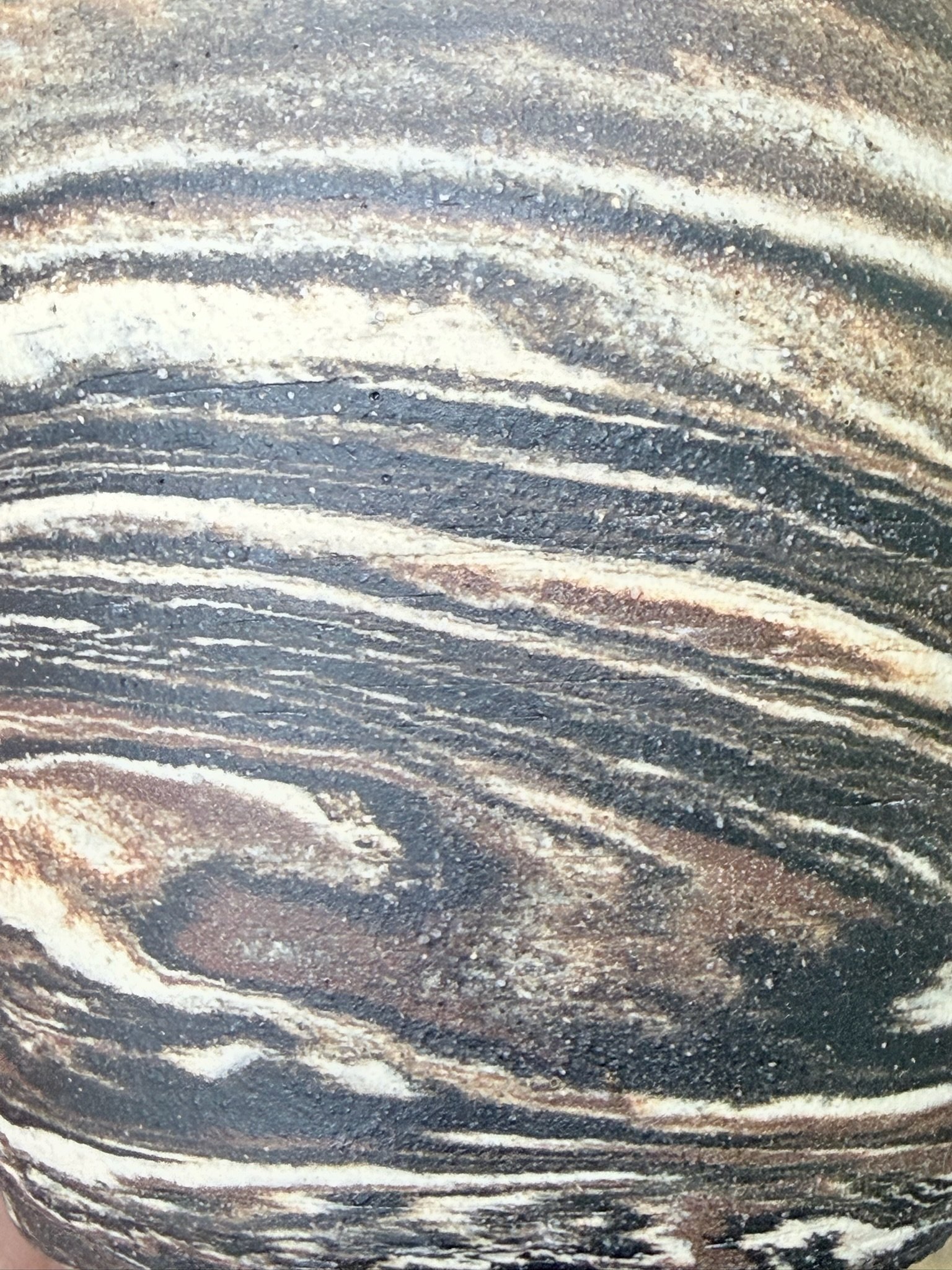Close-up of a polished, layered rock with wavy patterns in shades of black, white, and brown.