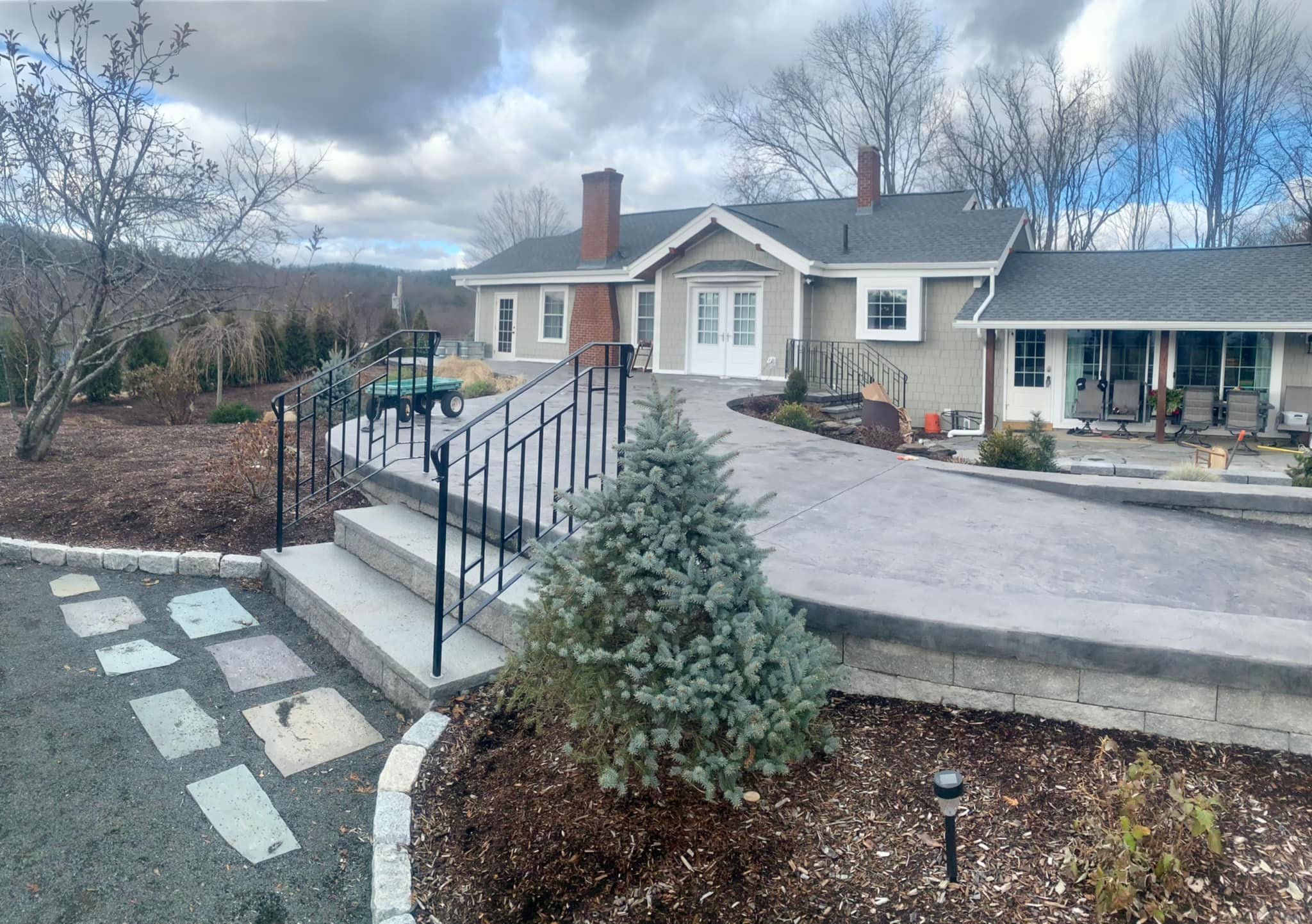 A custom hand-forged railing in front of a one story grey house.