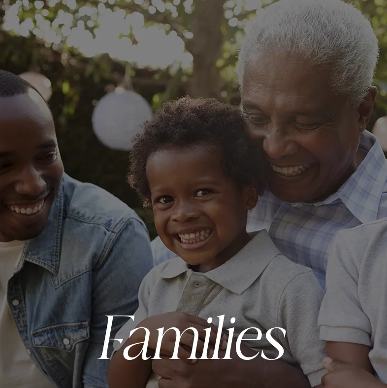 A multigenerational African American family enjoying a happy moment outdoors, with a young boy smiling broadly and an older man and woman celebrating their family. The word 'Families' is overlaid on the image.