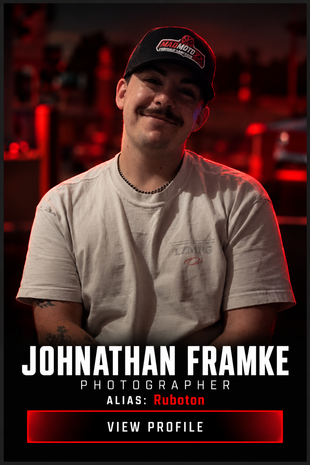 Portrait of photographer Johnathan Framke, alias Ruboton, wearing a black cap and white T-shirt in red lighting.