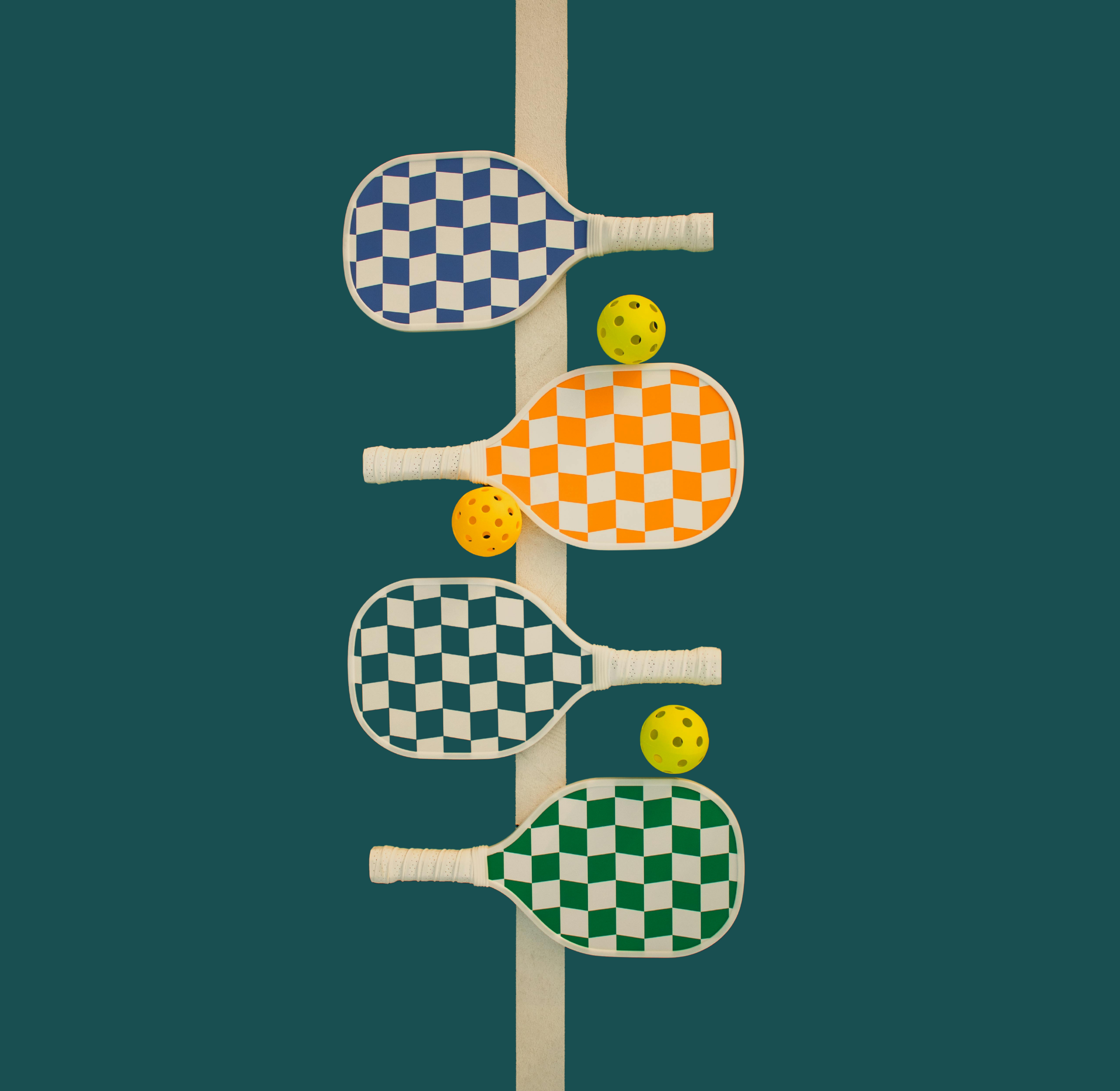 Four ping pong paddles with checkered patterns (blue, orange, black, green) align vertically along a white pole against a dark teal background, with three yellow balls with holes placed beside or below the paddles.