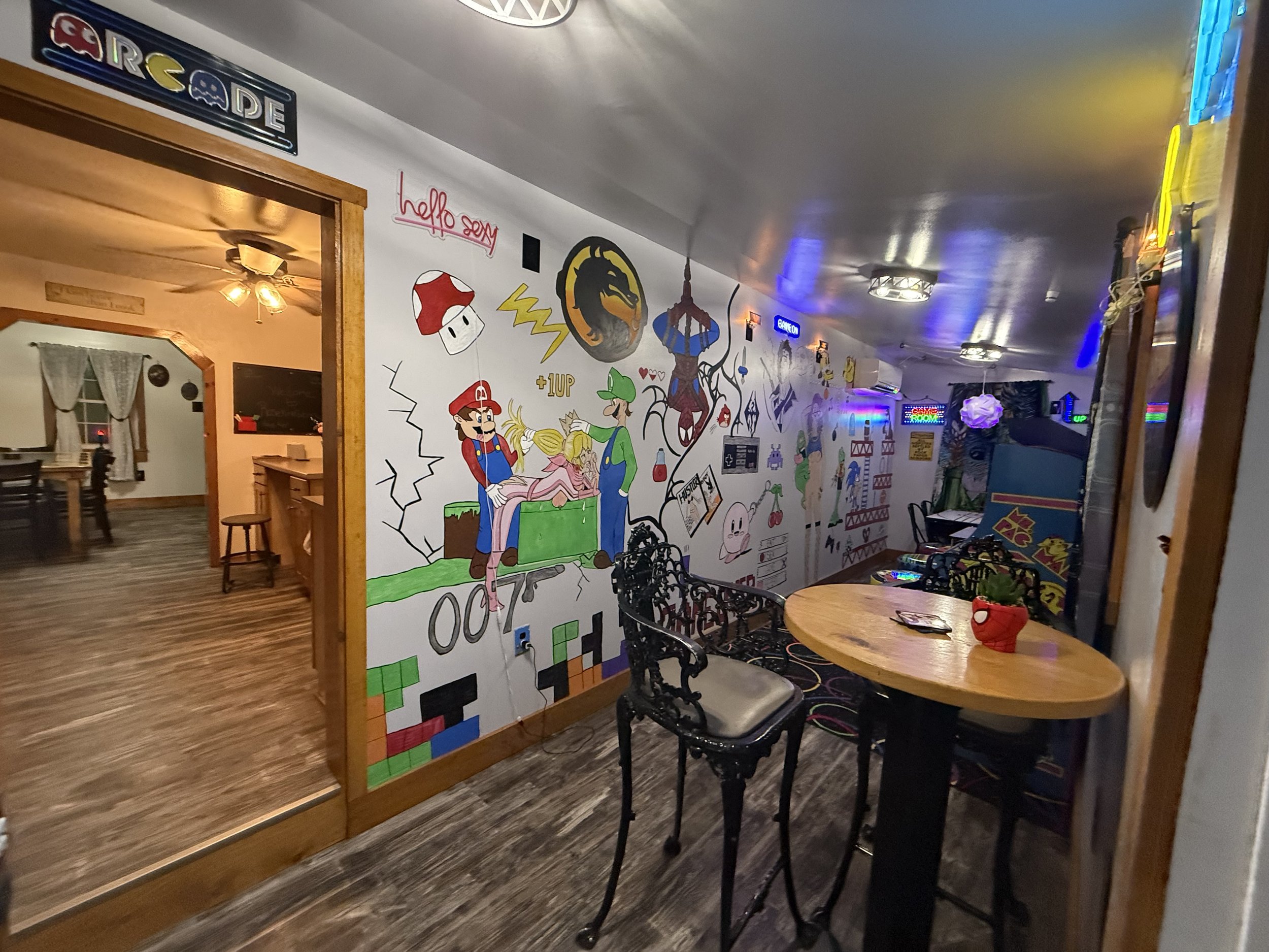 Arcade room with full wall mural, pub table and a card games