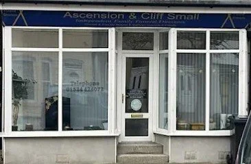 Exterior of a commercial building with large glass windows and a door, sign reading 'Ascension & Cliff Small' at the top.