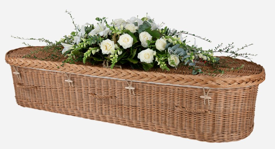 Wicker casket with white roses and greenery on top