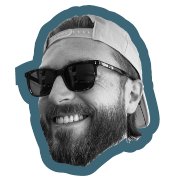 Close-up of a smiling man wearing sunglasses and a backward baseball cap.