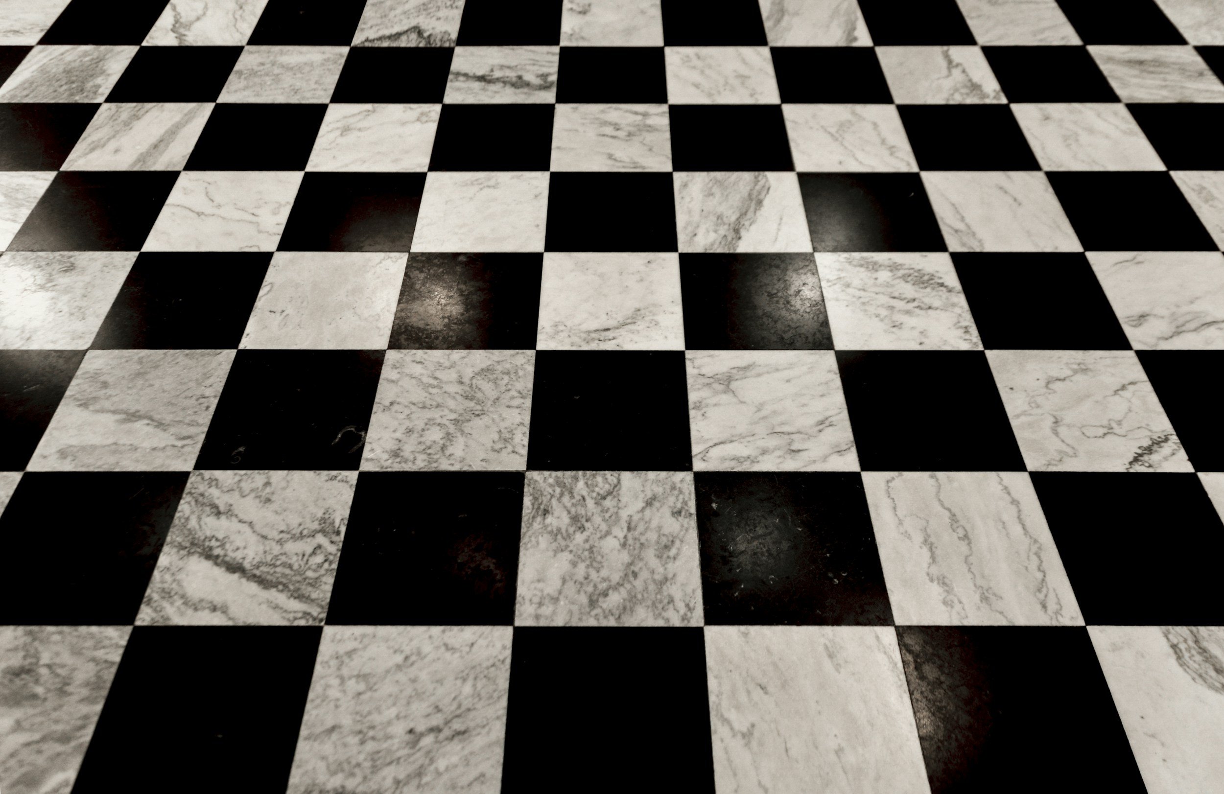Black and white checkered marble floor with squares arranged in a grid pattern.