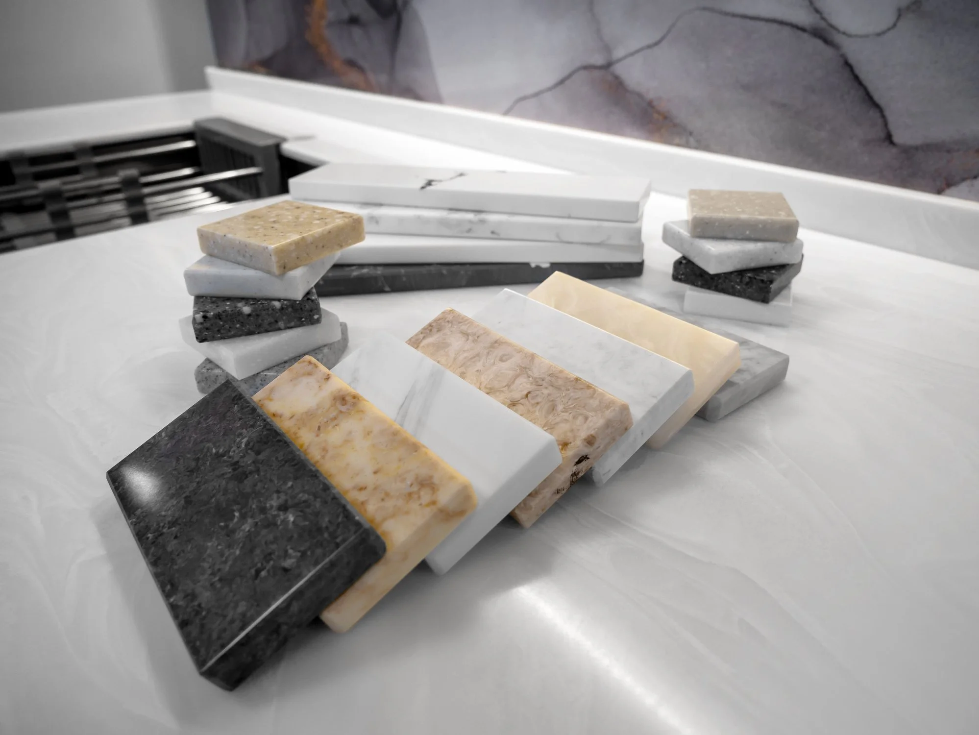 Stacked square marble slabs in various colors and patterns on a white surface.