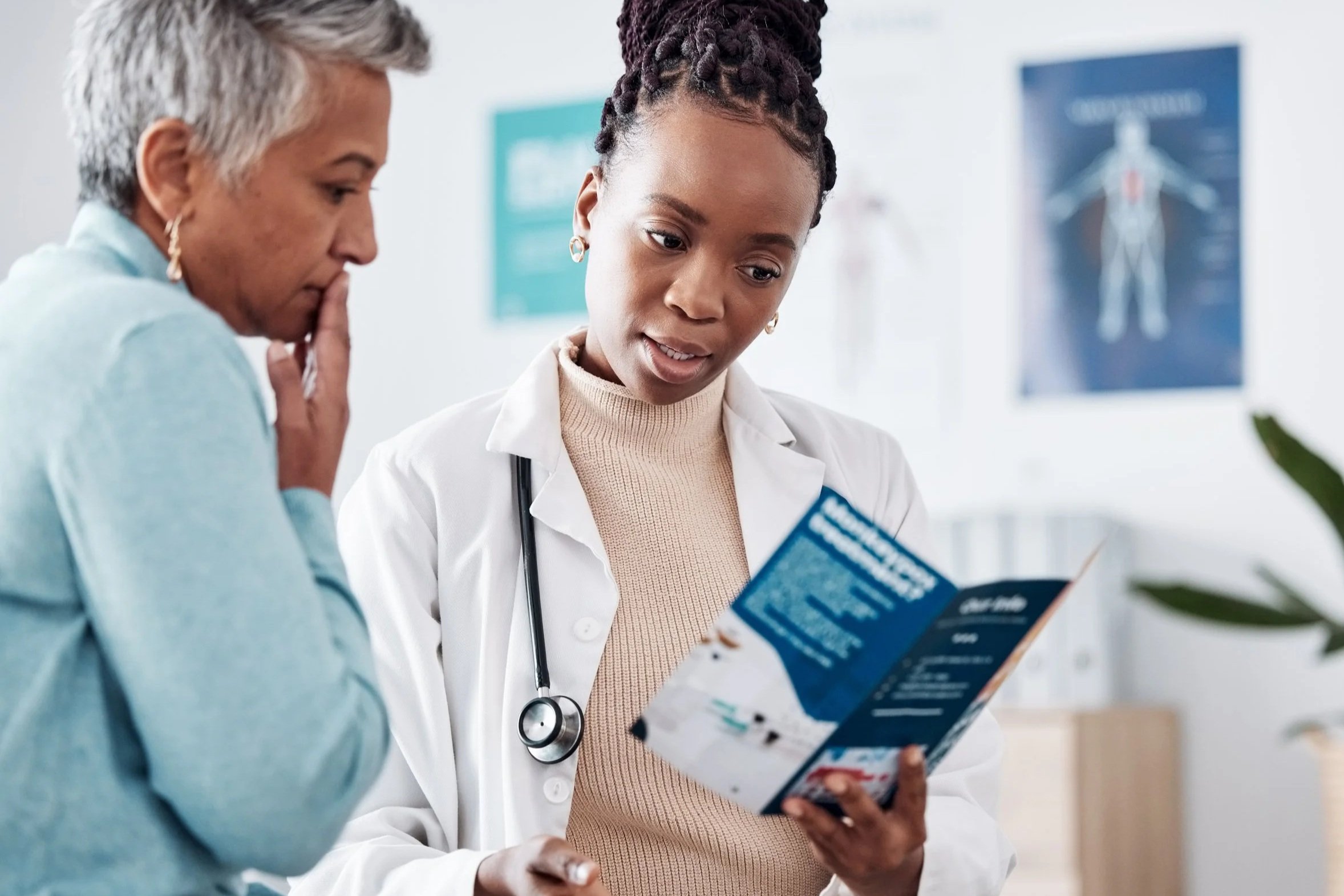 A female doctor showing a brochure to a patient in a medical office.
