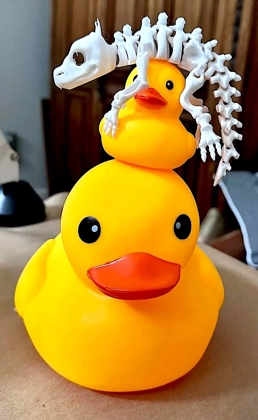 Two yellow rubber ducks stacked together with a small green 3D-printed dragon perched on top during a 3D printing project at Disorderly Studio.