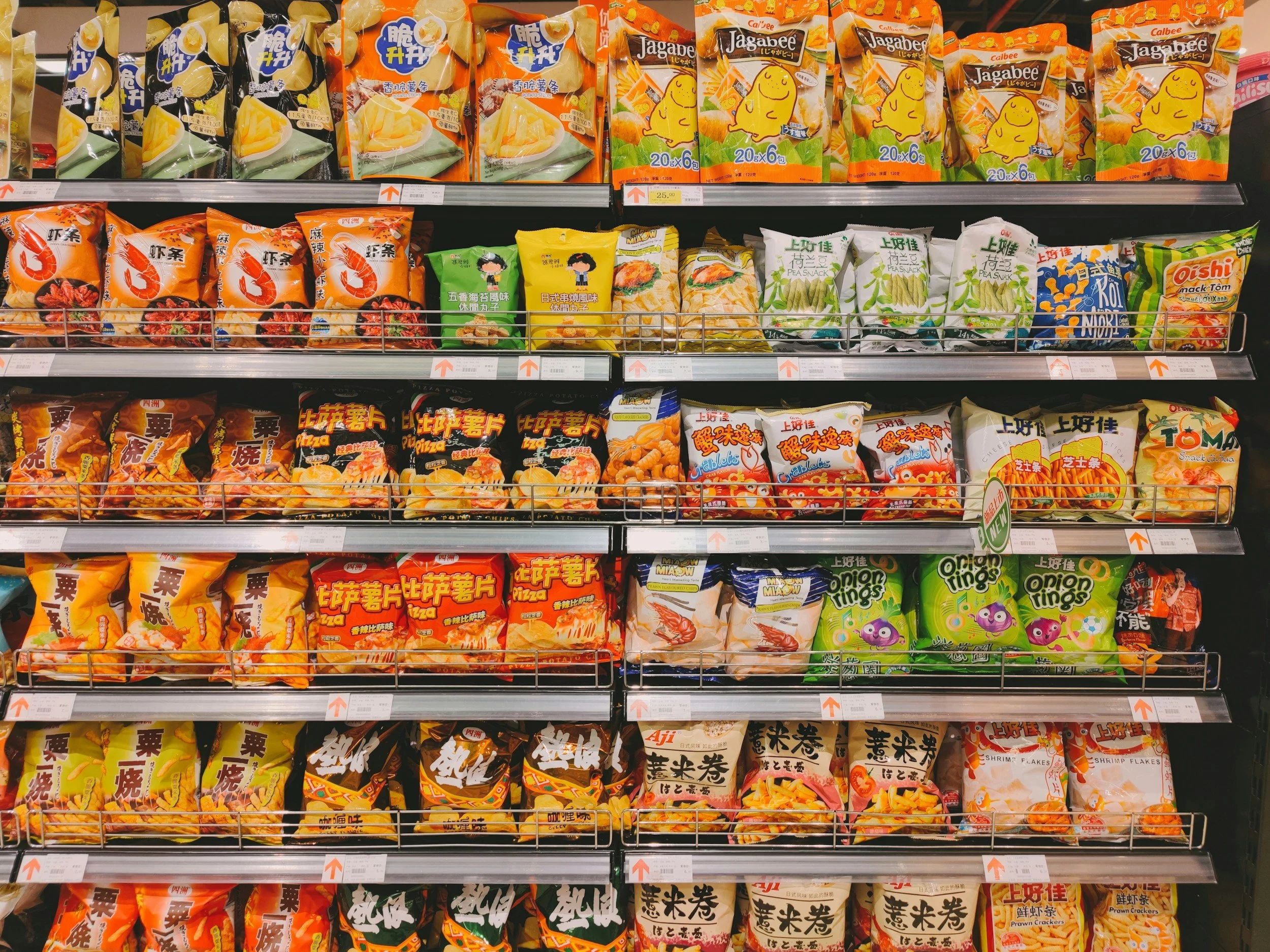 Shelves stocked with various snack and chip packages in a grocery store.