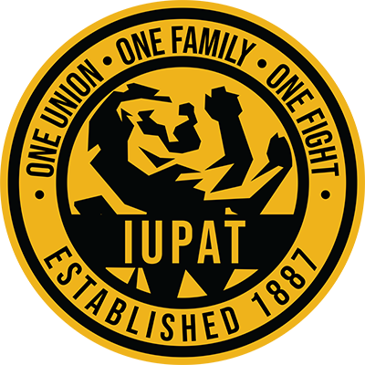 A circular emblem featuring a stylized image of a muscular man flexing his arm, with the words "TUPAT" below. The outer ring reads "One Union, One Family, One Fight," and "Established 1887."