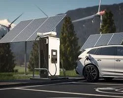 An electric vehicle charging station next to a white car in a parking lot with solar panels and a water sprinkling system in the background.