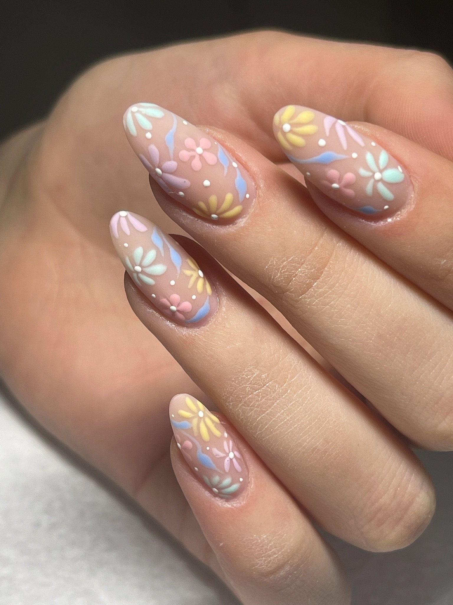 Unghie decorate con smalto trasparente con disegni di fiori colorati e dots bianchi.