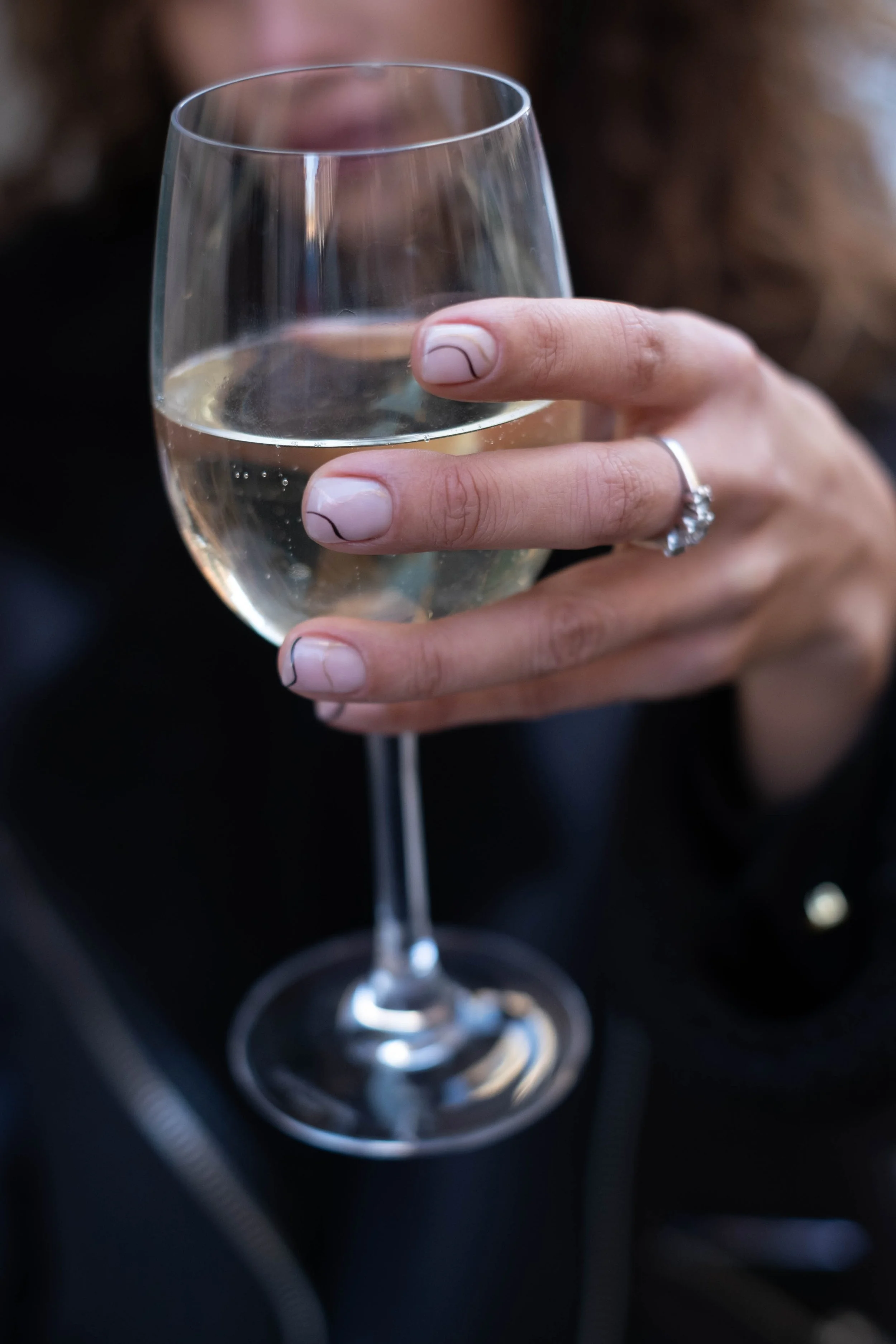 Una mano che tiene un bicchiere di vino bianco in un'auto