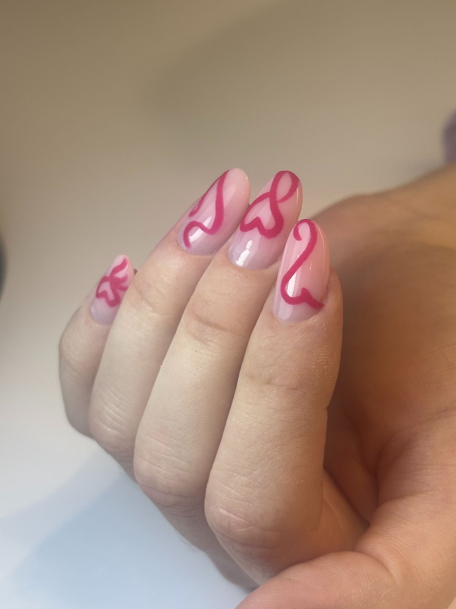 Unghie dipinte con base trasparente e motivi di linee rosse fluide.