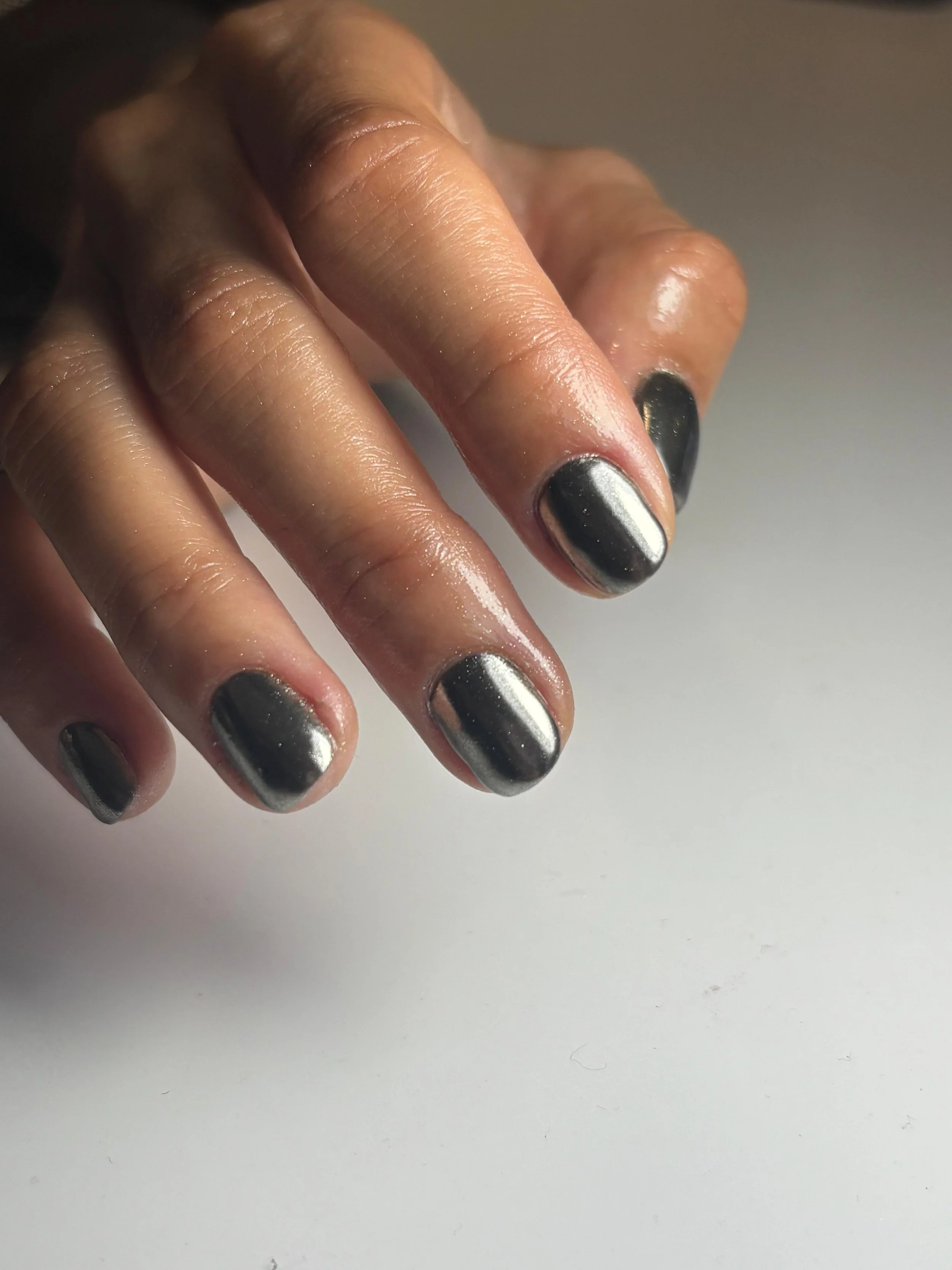 Dito con unghie dipinte di colore argento e pelle normale, posato su uno sfondo bianco