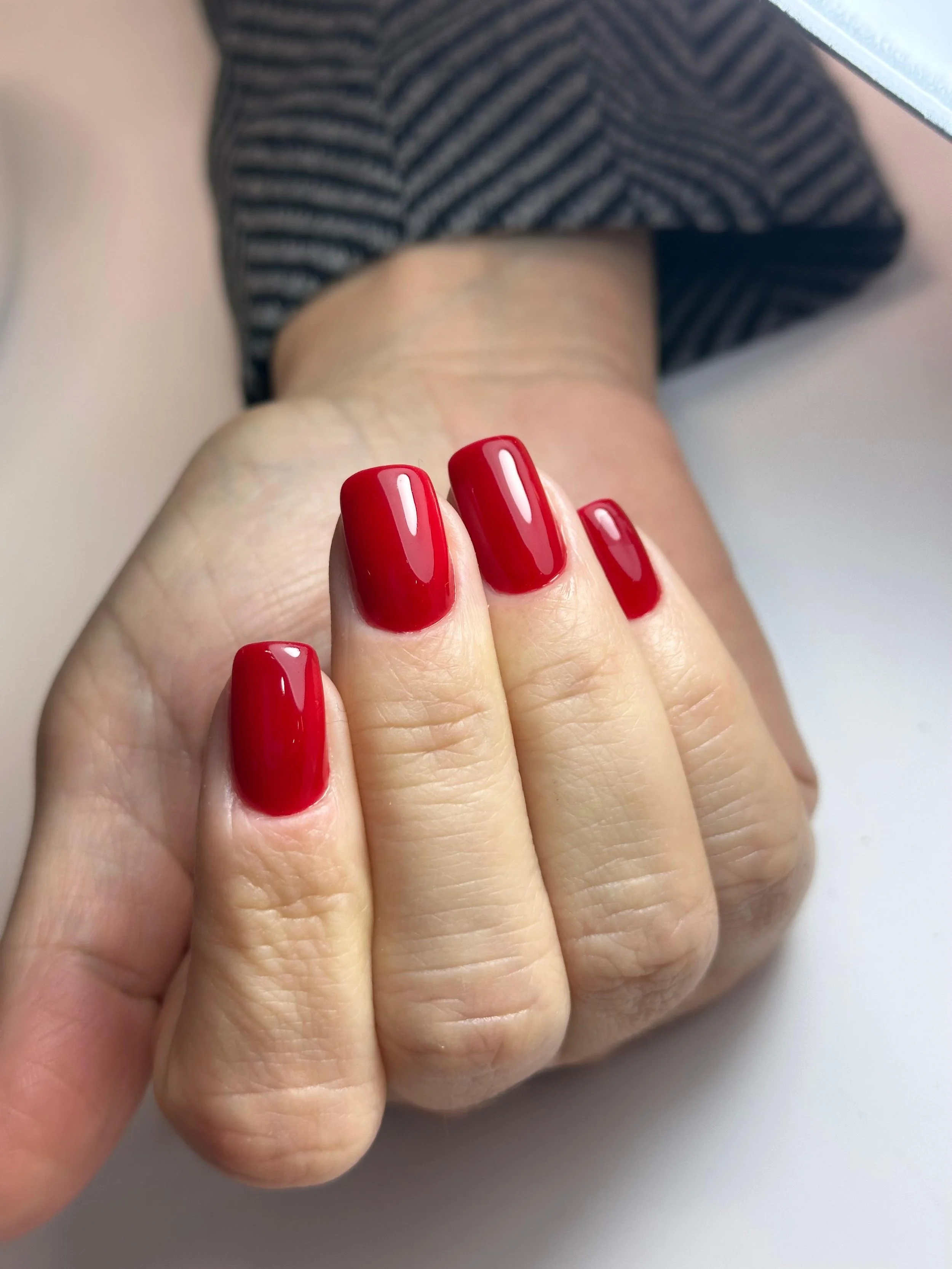 Unghie curate con smalto rosso su una mano.