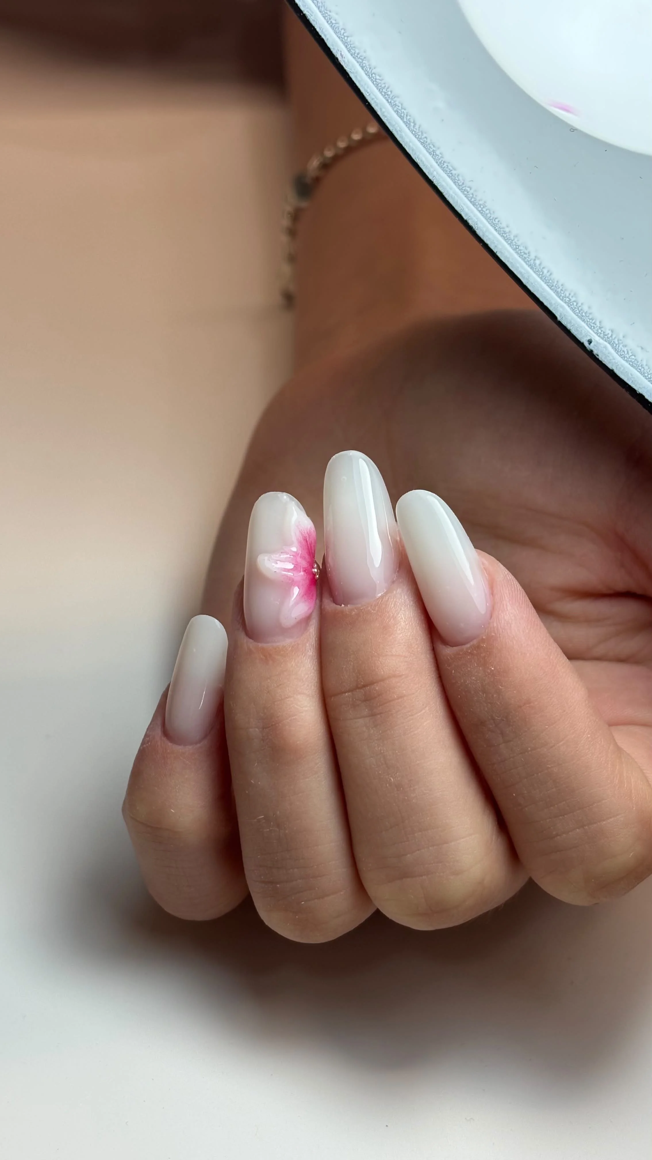Unghie con design floreale rosa su smalto bianco