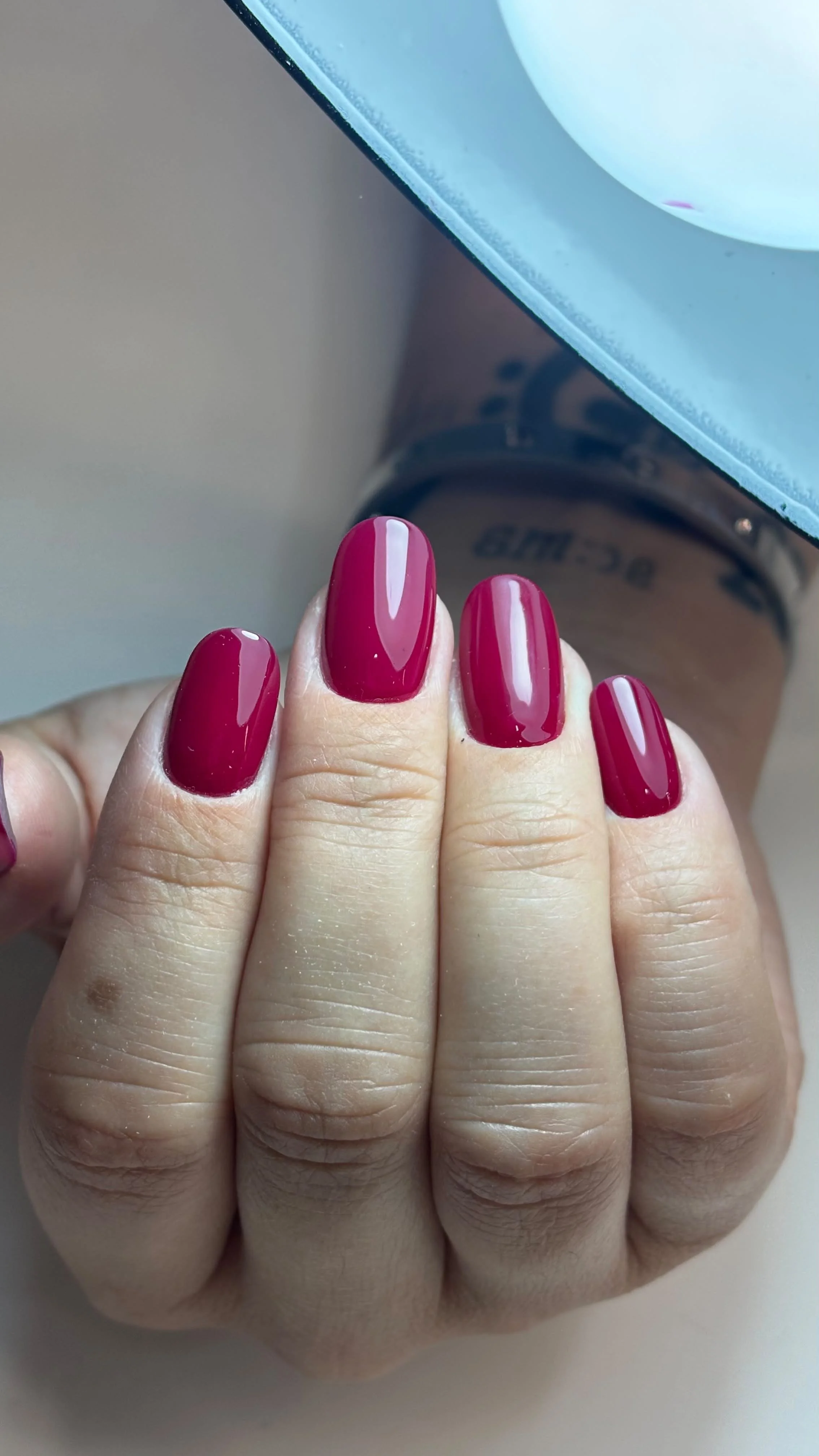 Unghie dipinte di rosso scuro con smalto lucido.