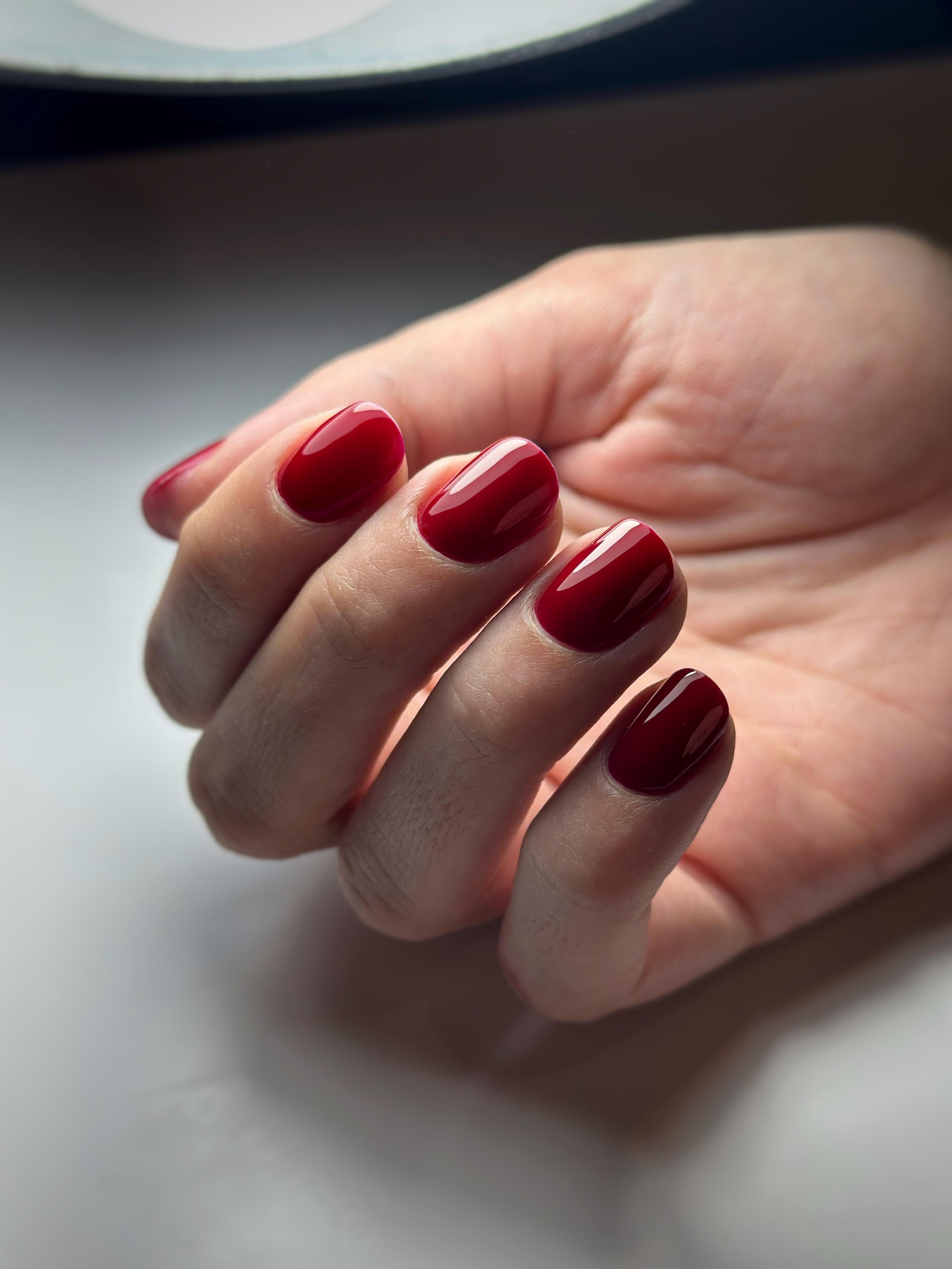 Unghia rossa smaltata sulle dita di una mano femminile con la pelle chiara, vista ravvicinata.