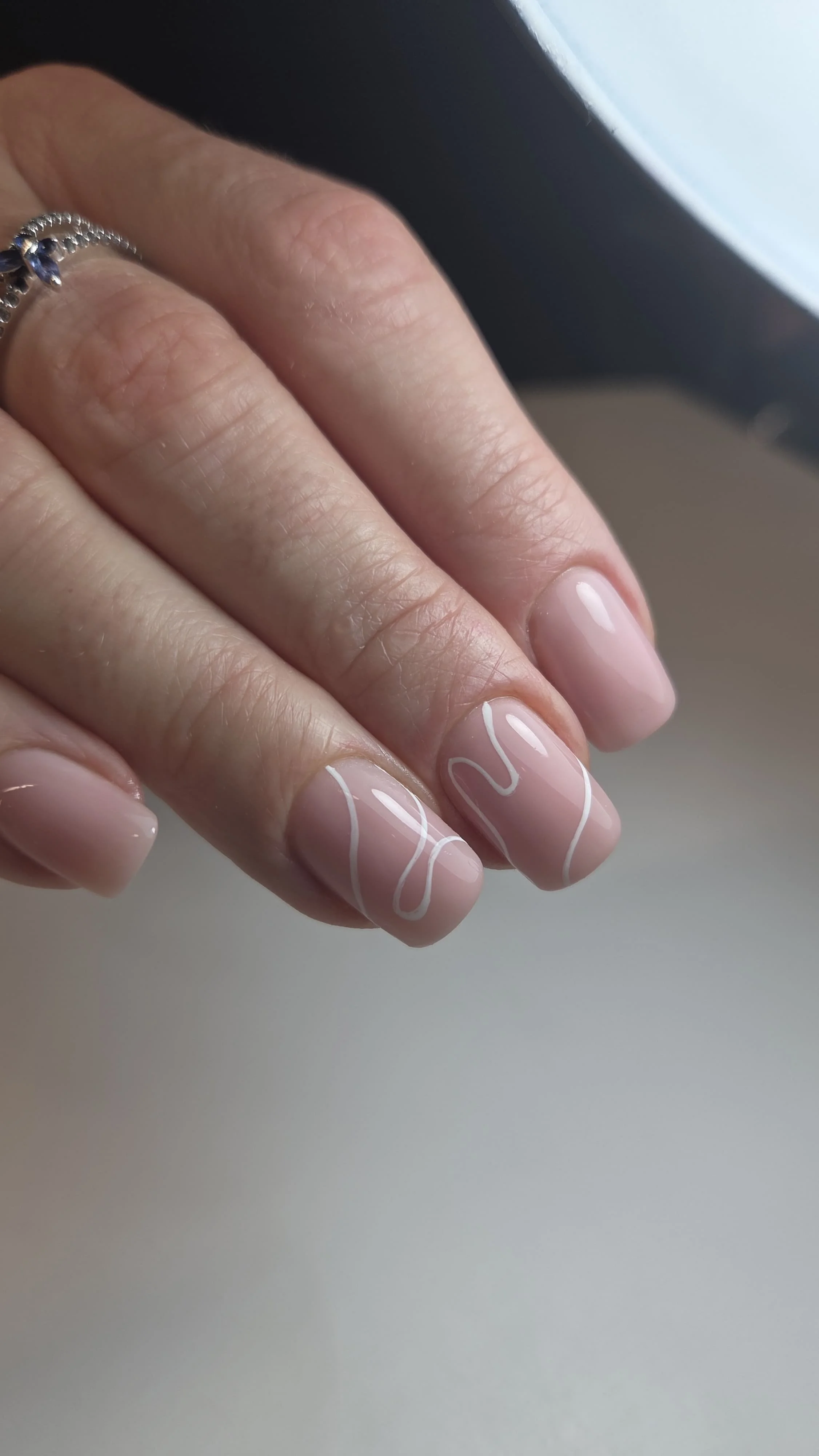 Unghie smaltate con decorazioni in bianco e mani con anello