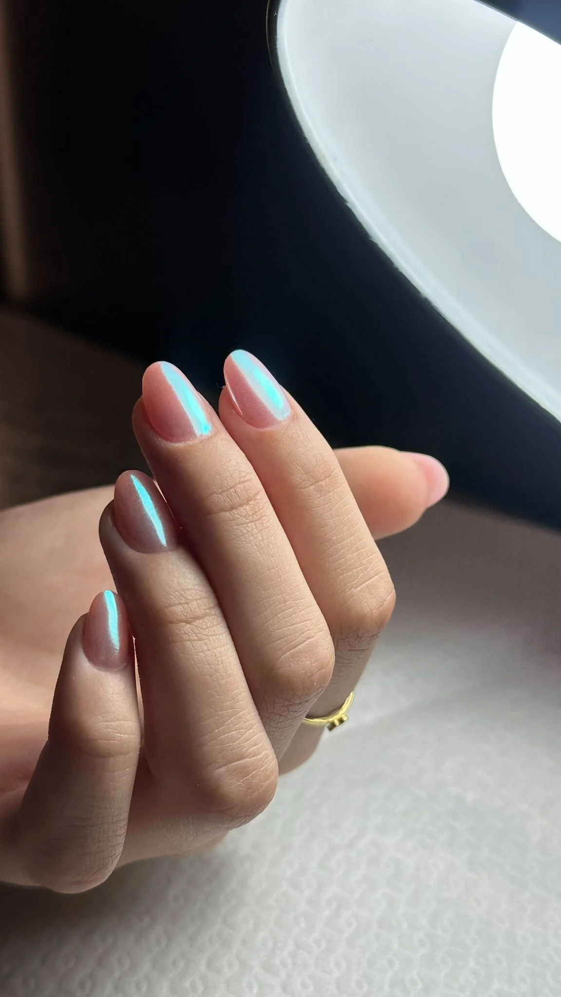 Dita di mani con unghie curate con smalto colorato e riflesso, una mano indossa un anello d'oro.