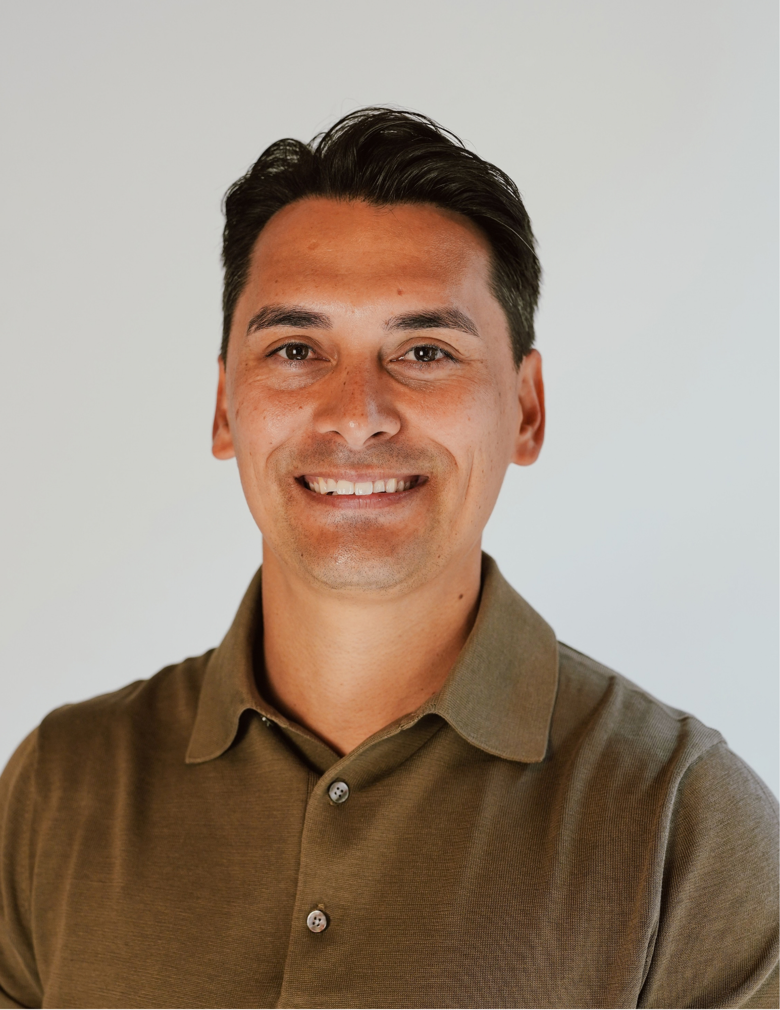 A smiling man with short dark hair, wearing a brown collared shirt, against a plain light-colored background. Jesse Haugh, licensed insurance agent with Benefits NW.
