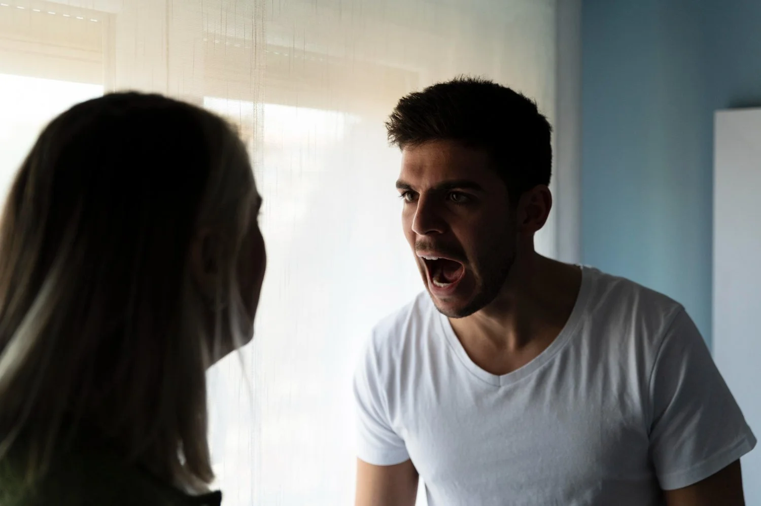 Man yelling at another person, representing domestic violence, intimidation, or verbal abuse