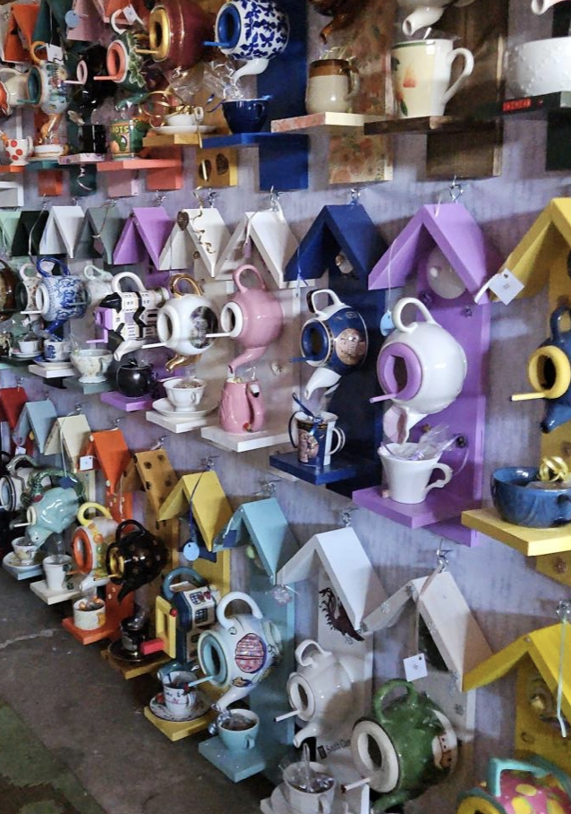 Once Again - Colorful teapots and cups displayed on wall-mounted shelves in a store.