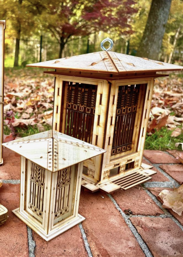 One Man, One Garage - Two wooden lanterns with intricate designs sitting on a brick pathway surrounded by fallen autumn leaves and trees in the background.