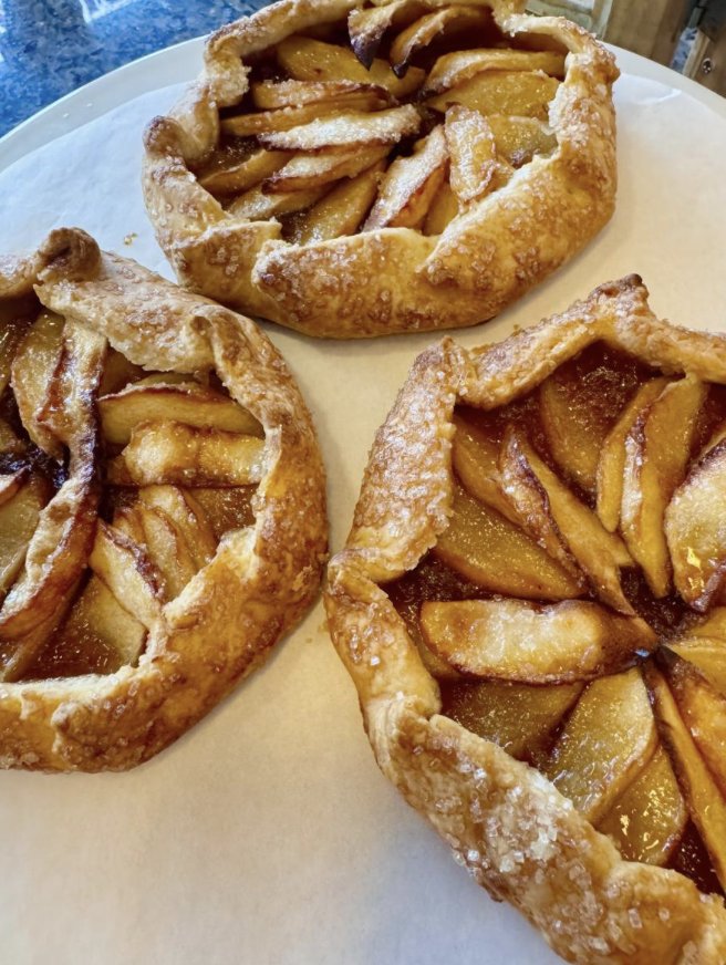 Dulce Vegan Bakery - Three individual apple galettes with golden, flaky crust and caramelized apple slices inside, on a white surface.