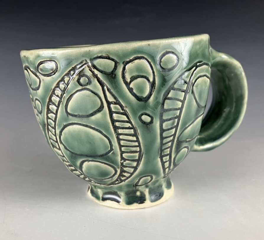 Lillian Bolster Pottery - Green ceramic cup with black line patterns and a handle, decorated with abstract designs.