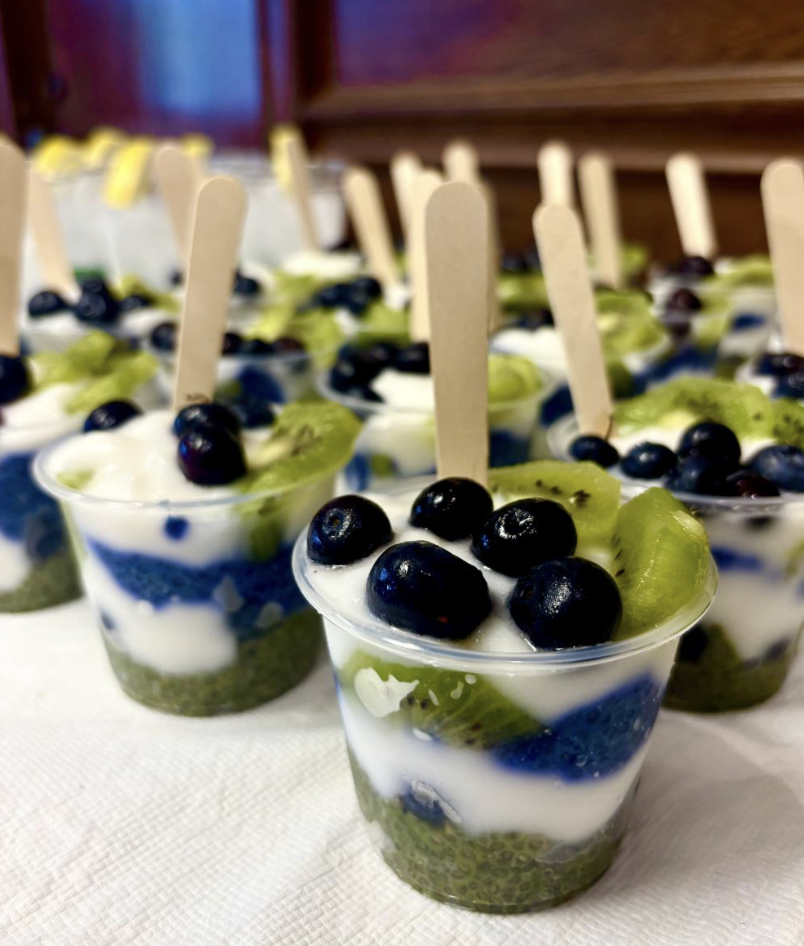Hibve Holistics Juice Bar - Individual layered desserts in clear cups topped with blueberries and kiwi slices, served with wooden sticks.