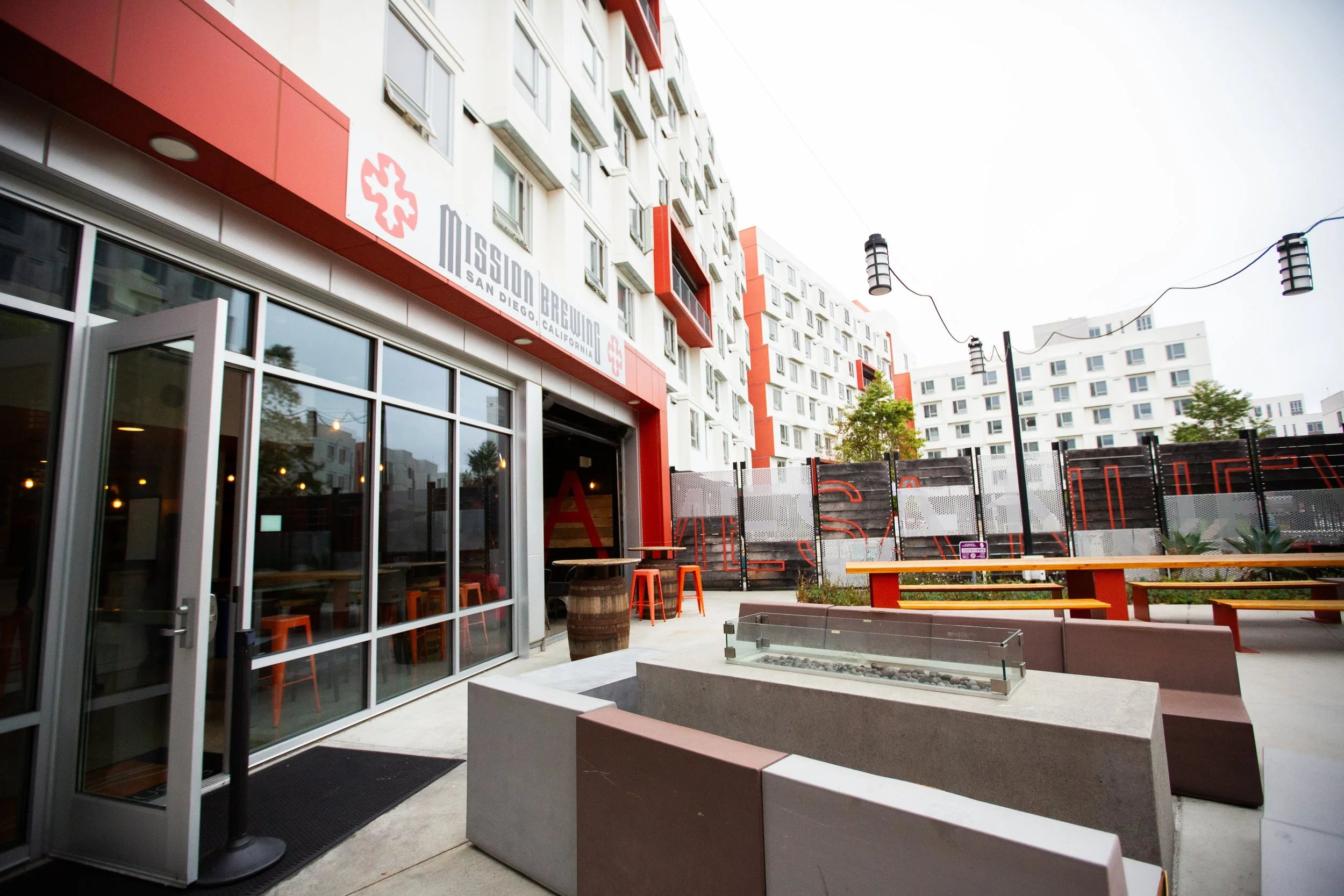 Outdoor patio area of a Mission Brewing UCSD with tables, benches, and string lights.
