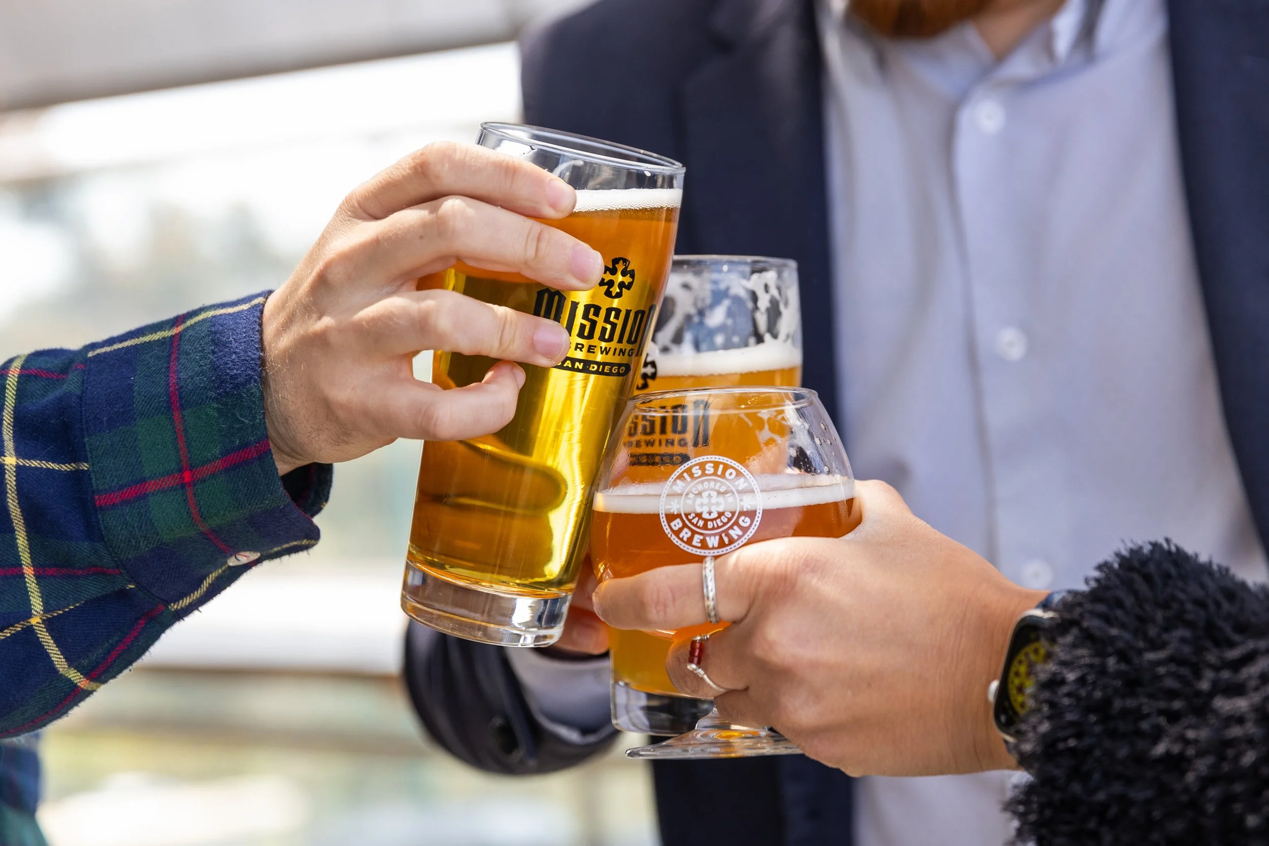 People clinking glasses of beer in a toast at a social gathering.
