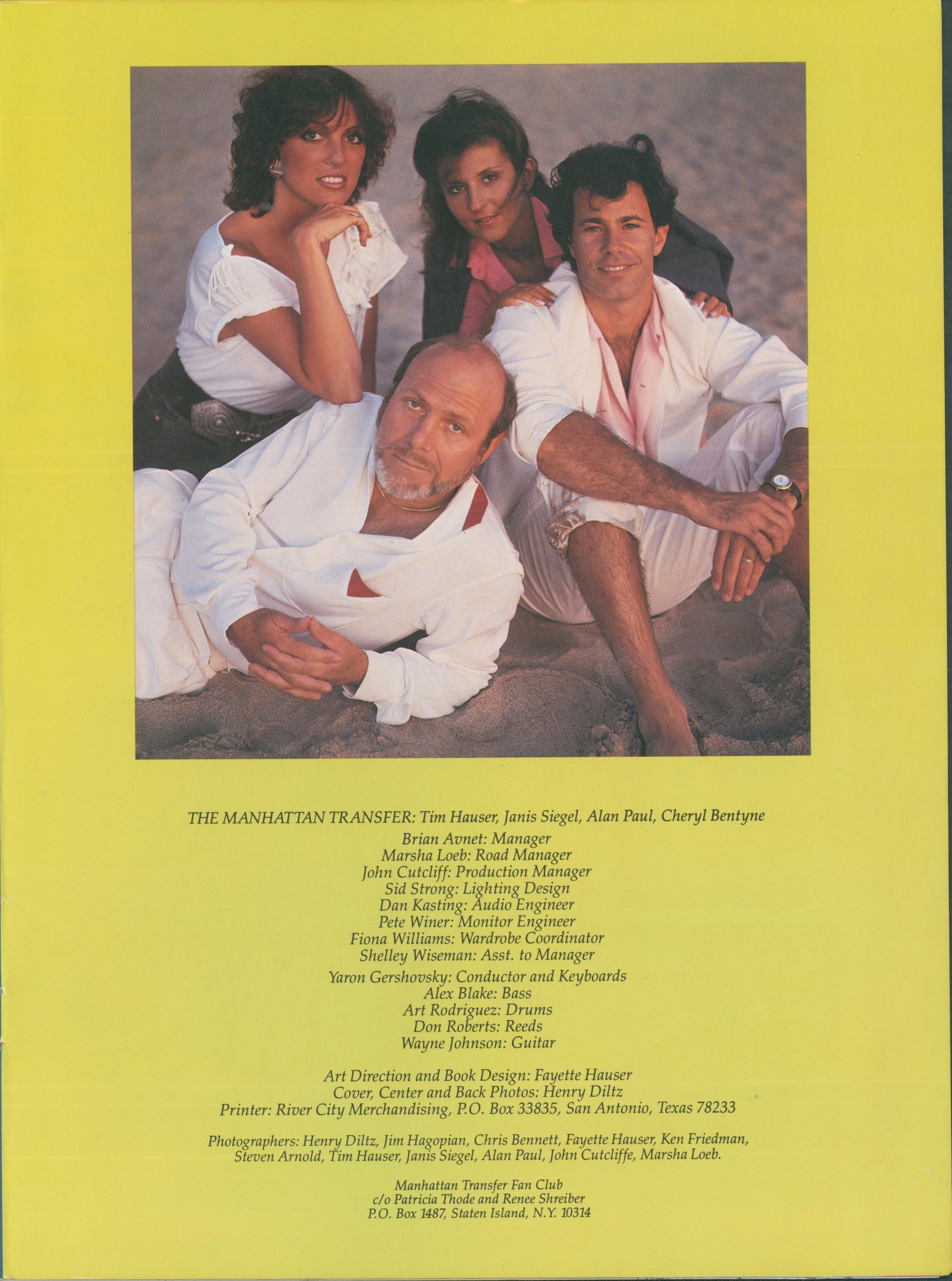 A promotional poster for the TV show "Manhattan Transfer" featuring five characters sitting or lying on sandy ground, with a yellow border and show credits listed below.