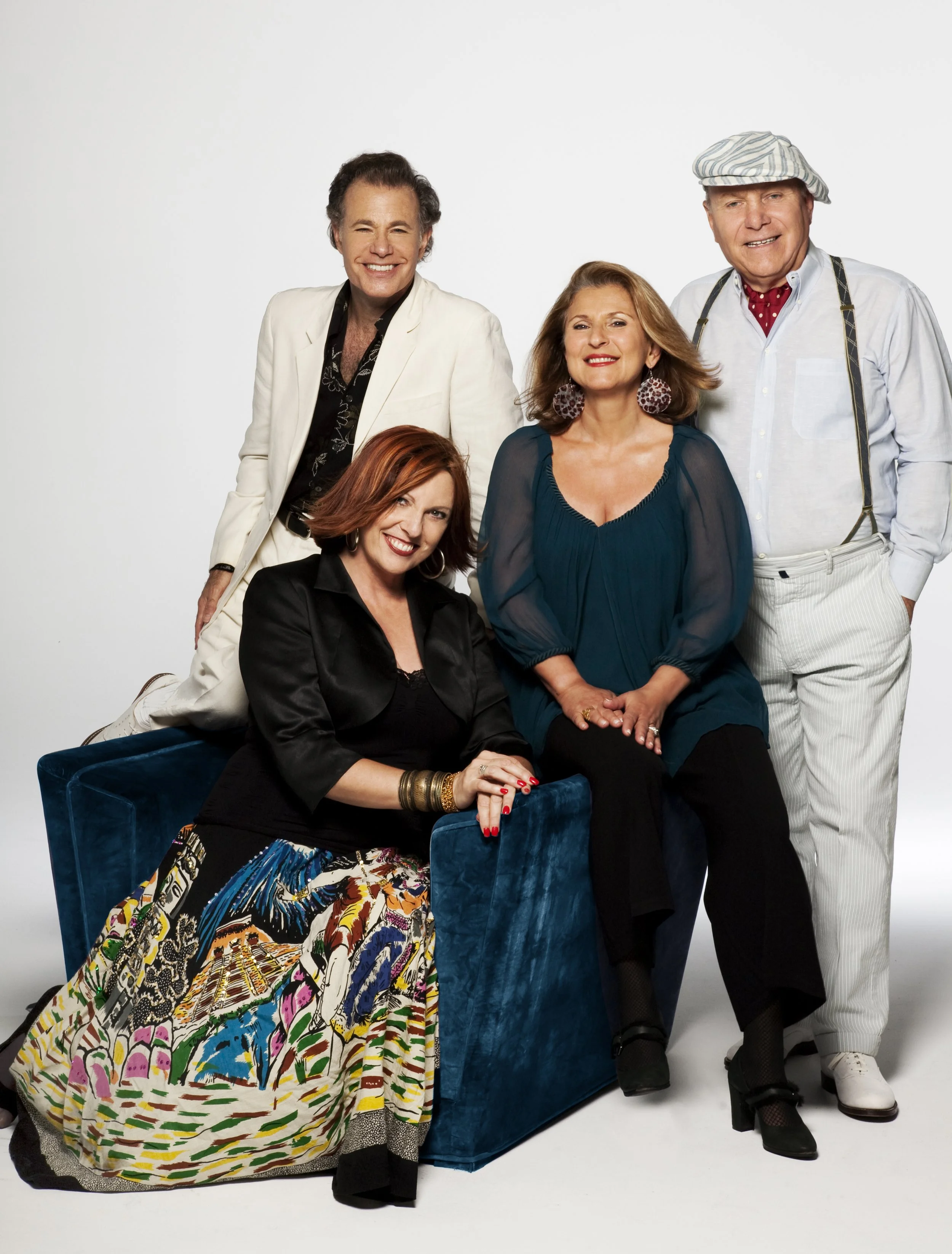 Group of five people dressed in colorful and fashionable clothing, posing together in a studio with a white background.
