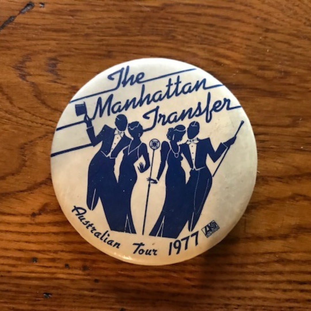 A vintage button badge from The Manhattan Transfer's 1977 Australian tour, featuring stylized silhouettes of four people in formal attire holding musical instruments.